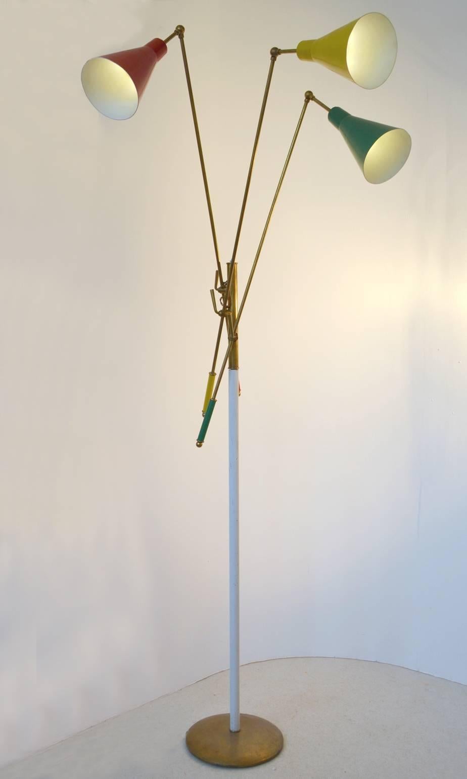 Tall multi colored Italian 1950s floor lamp in the style of Arredoluce with three articulating arms with shades and counterweights in enamel red, yellow and green attached to a main central stem in brass and cream enamel on a brass base. Each arm