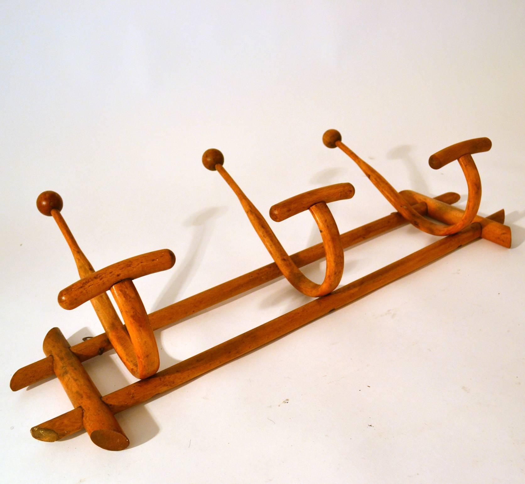 Early 20th century wooden coat rack with three large hooks for a coat and hat.