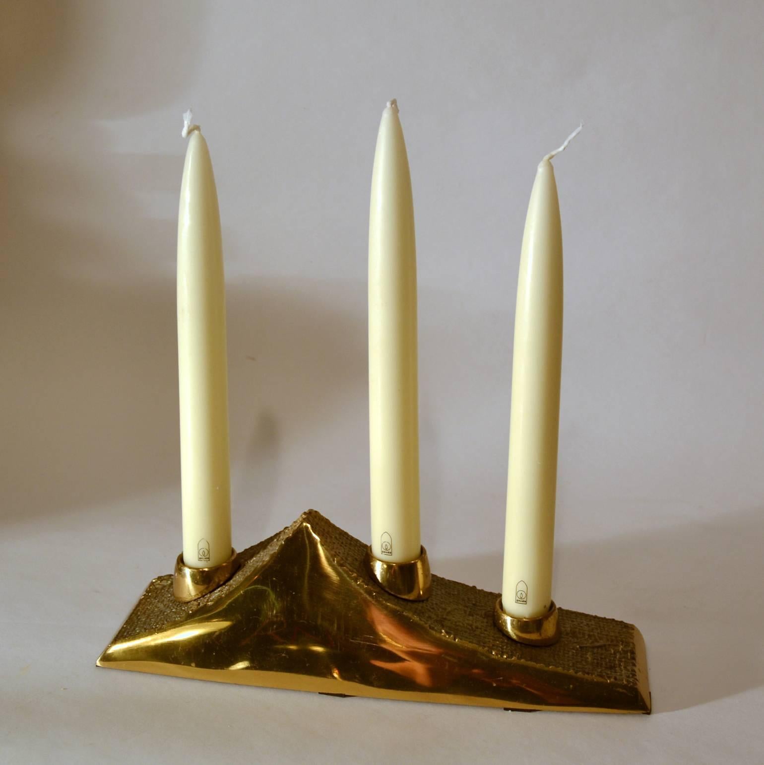 Brutalist candlestick for three candles with the texture of burlap imprinted in part of the candelabra contrasted with a high polished sheen. The bronze cast candlestick is part of a group of high quality cast items we present signed by Antonella