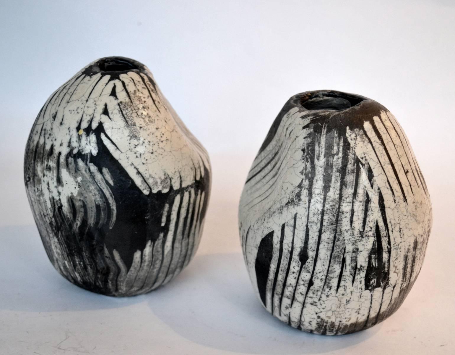 Two small hand formed ceramic vases. They are Raku fired black ceramic, hand-painted white glaze with eggshell cracking effect. The irregular veins in the glaze are created by Raku firing technique, a unique form of pottery making with its origins