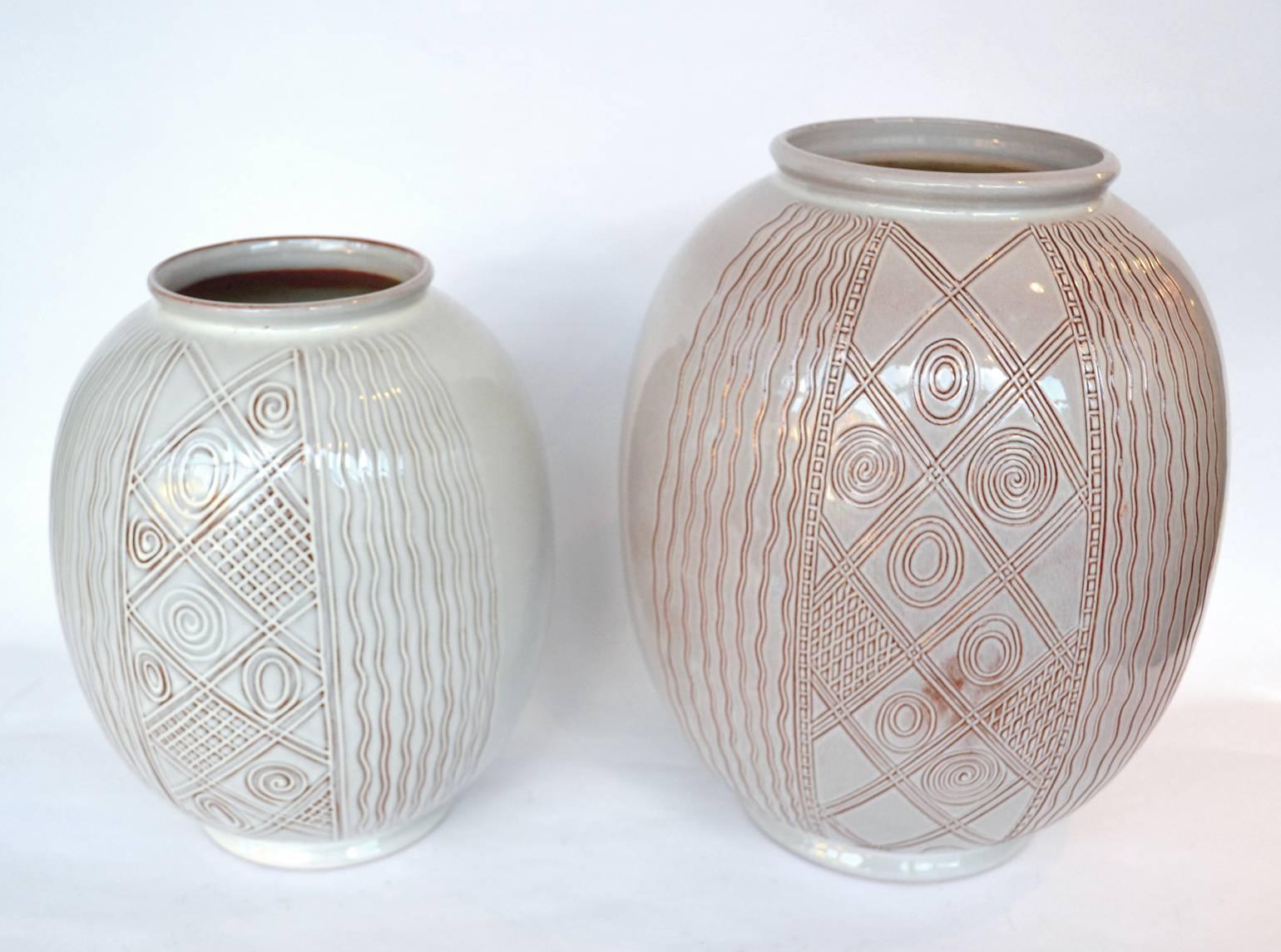 Two individually decorated vases by the Dutch company Sphinx in Maastricht, 1950s.
The undertone is orange and the top glaze is white. After turning them they have been hand decorated by an engraved pattern inspired by Art Deco ornaments. This
