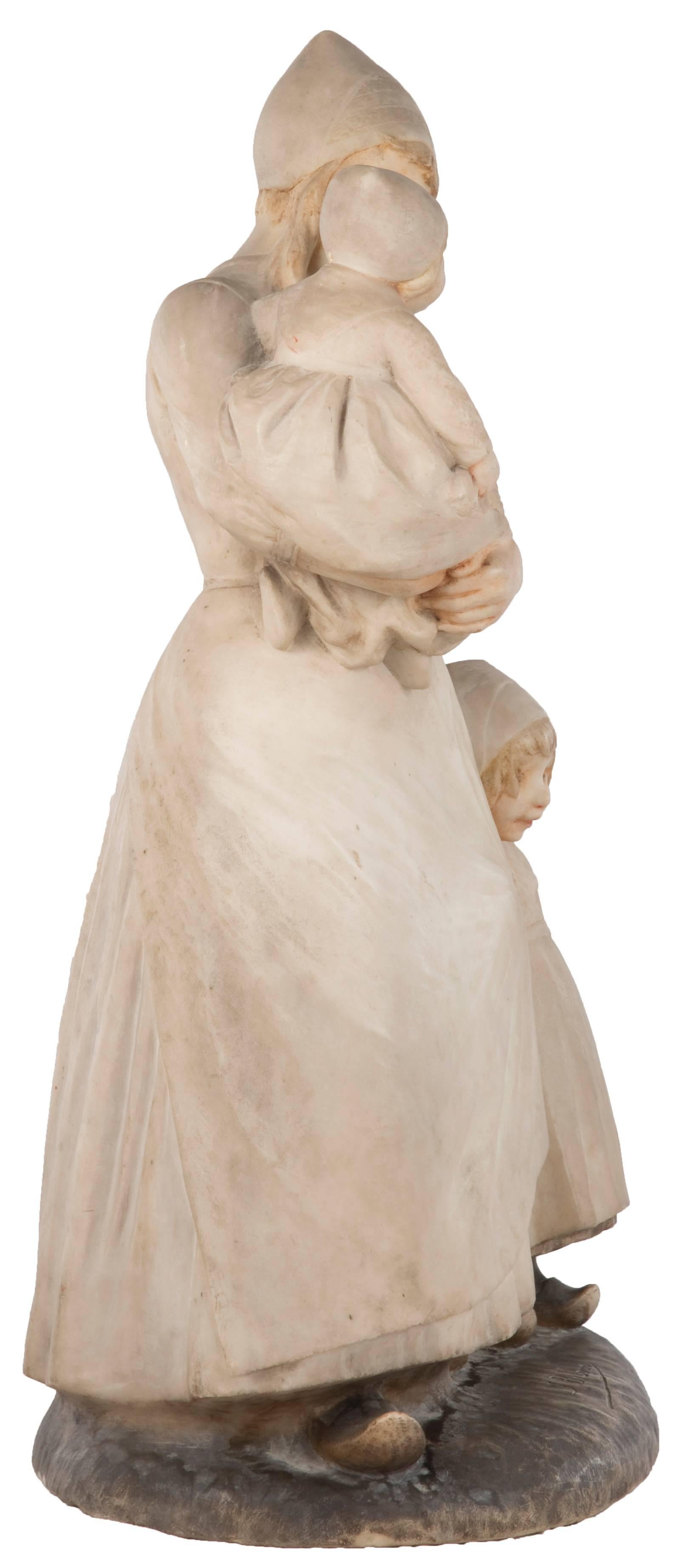 A 19th century Dutch figural group of a young mother with two young children, dressed in traditional Dutch dress and wooden clogs, with golden hair emerging from beneath their caps. The image is one of intimacy and maternal love. Top of base signed