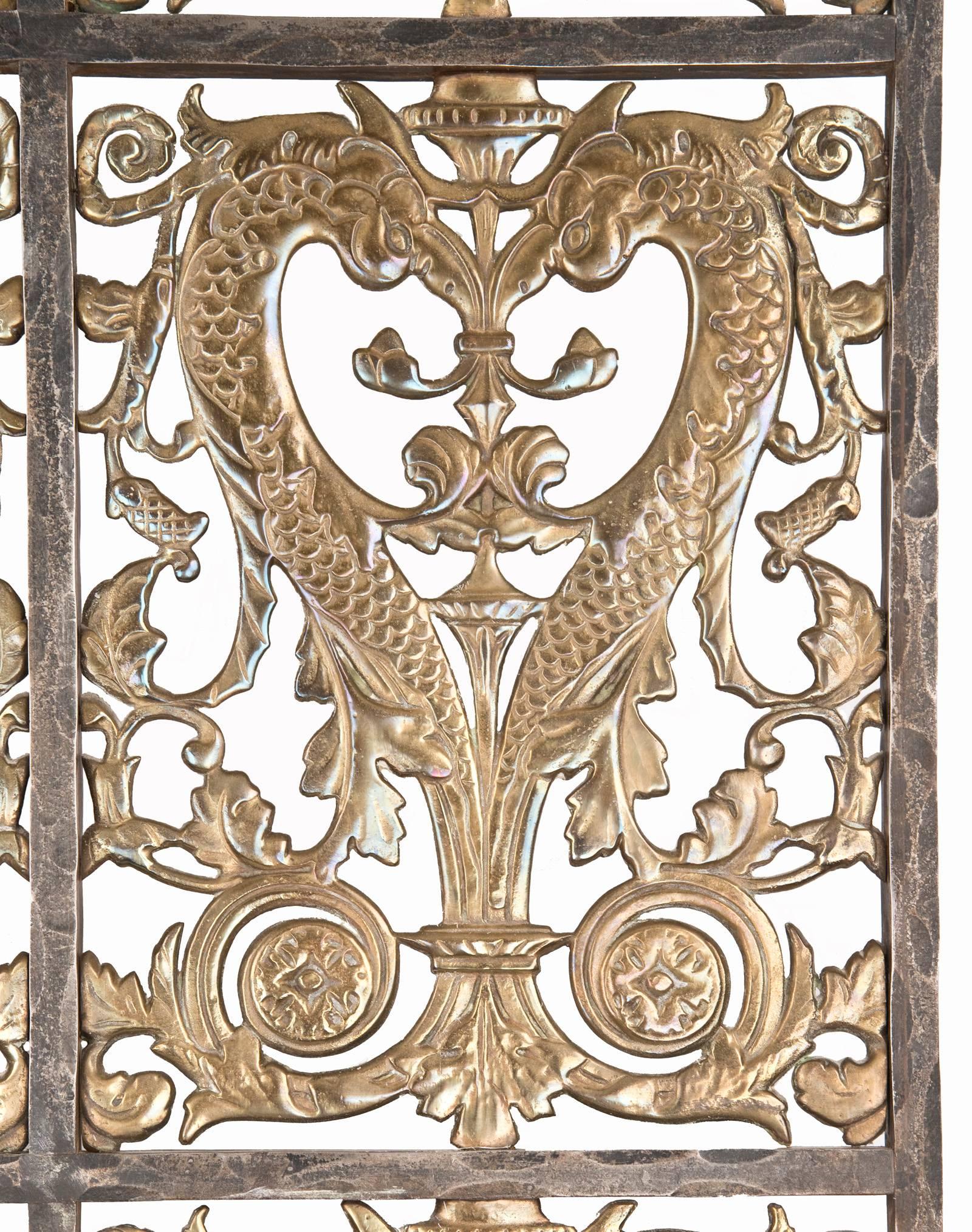 An imposing, yet elegant, pair of Art Deco entry gates constructed with an iron frame and repeating open panels of cast brass diving dolphins motif with thistles and scrolling foliate.