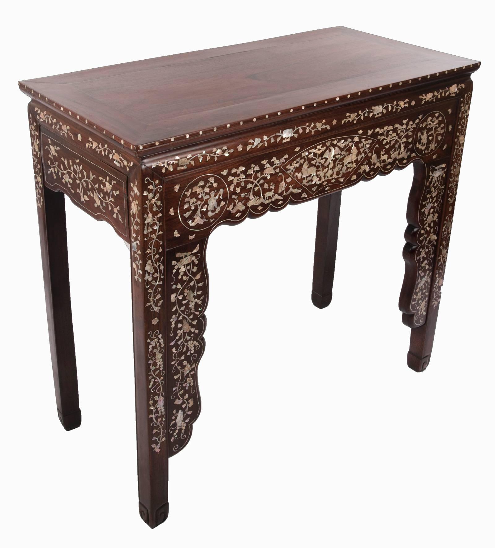 A 19th century Chinese hardwood and mother-of-pearl inlaid console table. The plain tabletop is a compliment to the elegantly adorned frieze of scrolling florals above the apron that is ornately decorated with natural vegetation, animals and Chinese