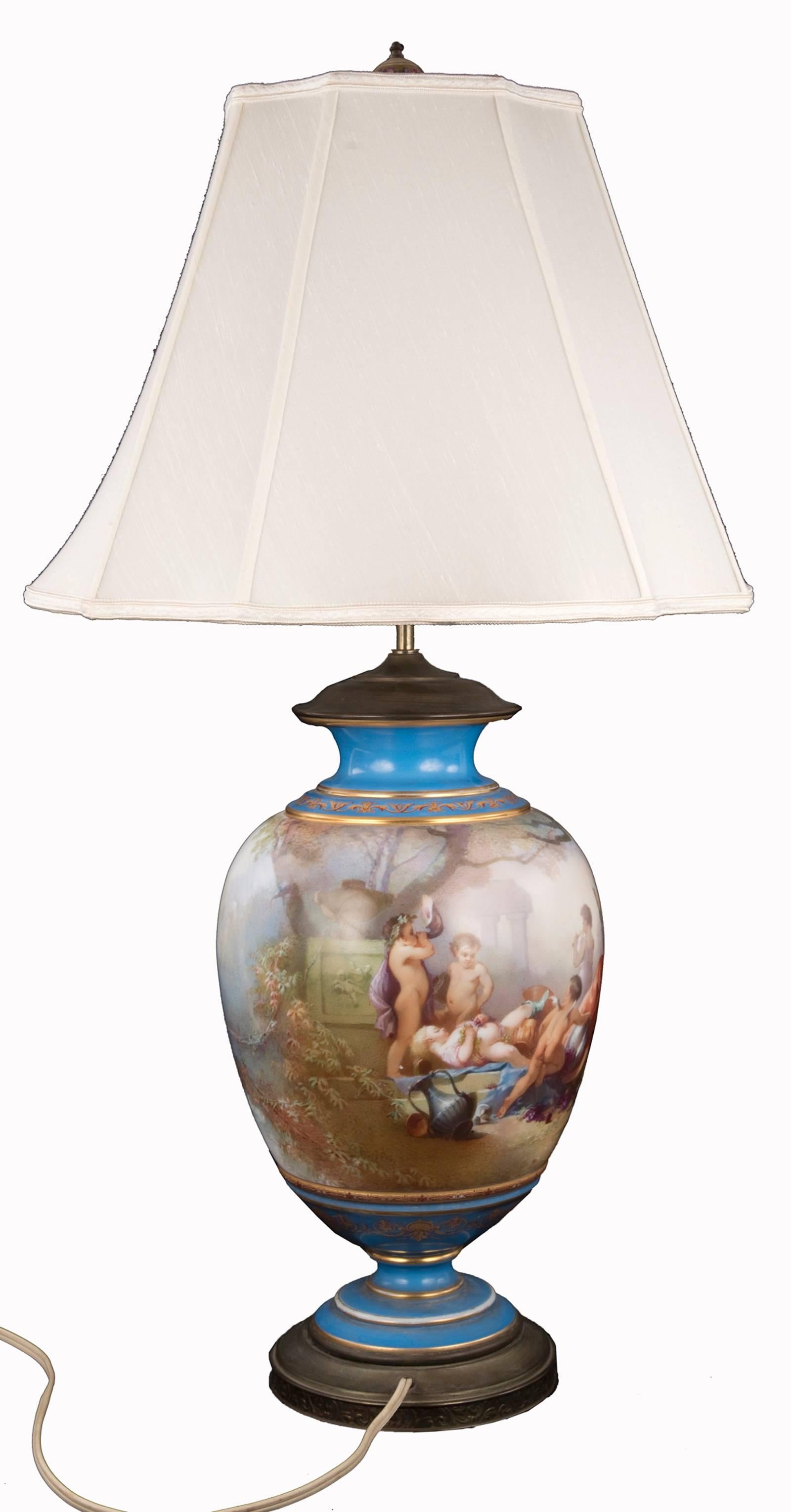 A 19th century lamped vase of baluster form by Sevres. Bacchus and several putti are depicted enjoying jars of wine in a garden setting, surrounded by large architectural elements and urns just visible in the misty environ. Cerulean blue painted