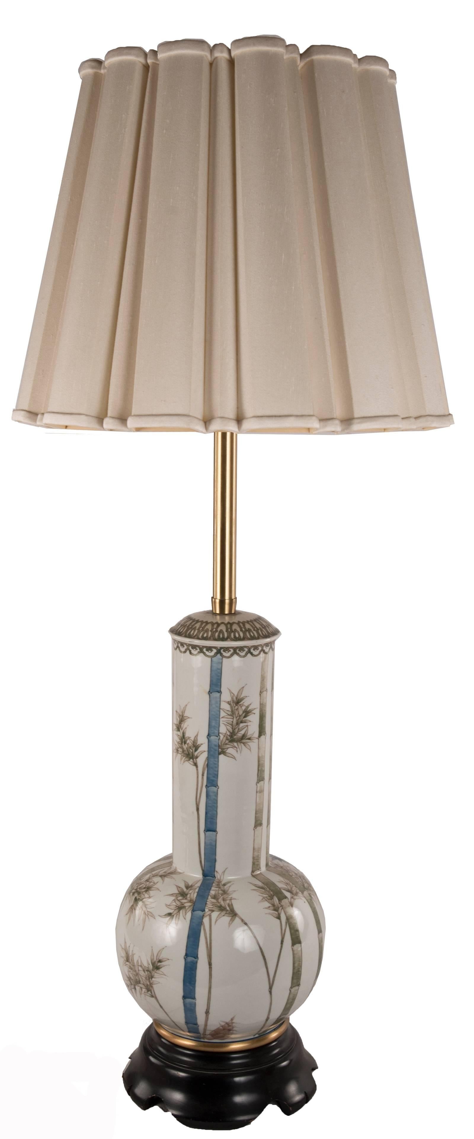 A 19th century Chinese white glaze bottle vase, the globular body raising to a long neck supported by a short brass foot rim and mounted on a turned and carved ebonized wooden base. The body and neck is decorated with bamboo shoots and leaf design
