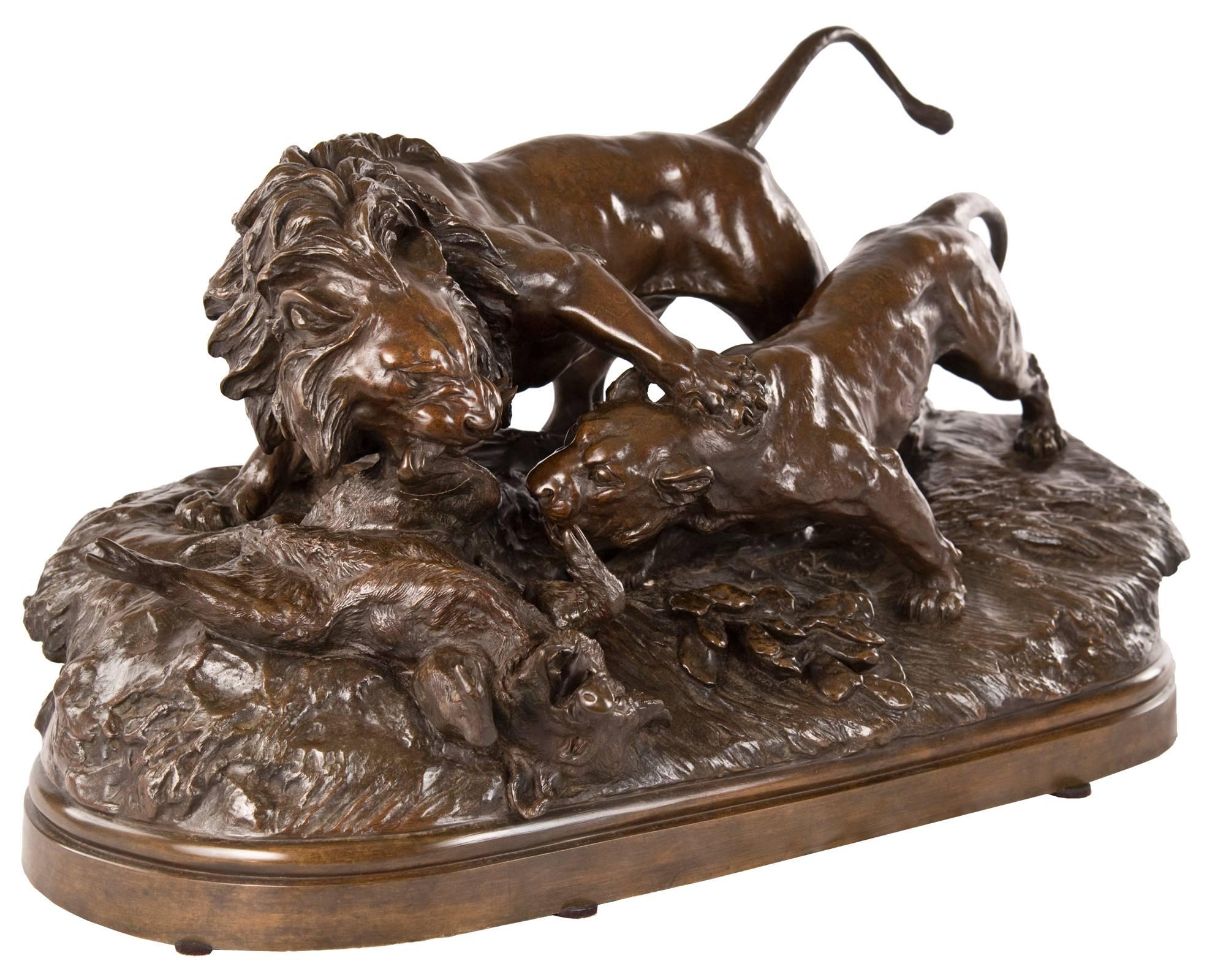 A French 19th century bronze group full of energy and movement depicting a lion and a lioness fighting for a boar, raised on a naturalistic ground atop an oblong stepped base. The lion grips the leg of the boar in his jaw, with his weighty paw on