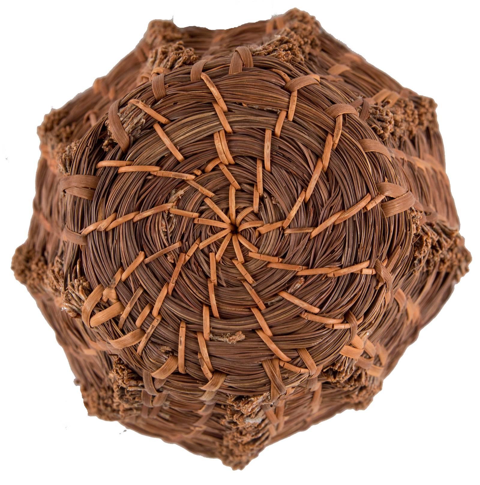 Coils of pine needles are bound together in layers with exposed ends that, when placed on top of one another, form a textural linear decorative element that balances that utilitarian functionality of the basket.