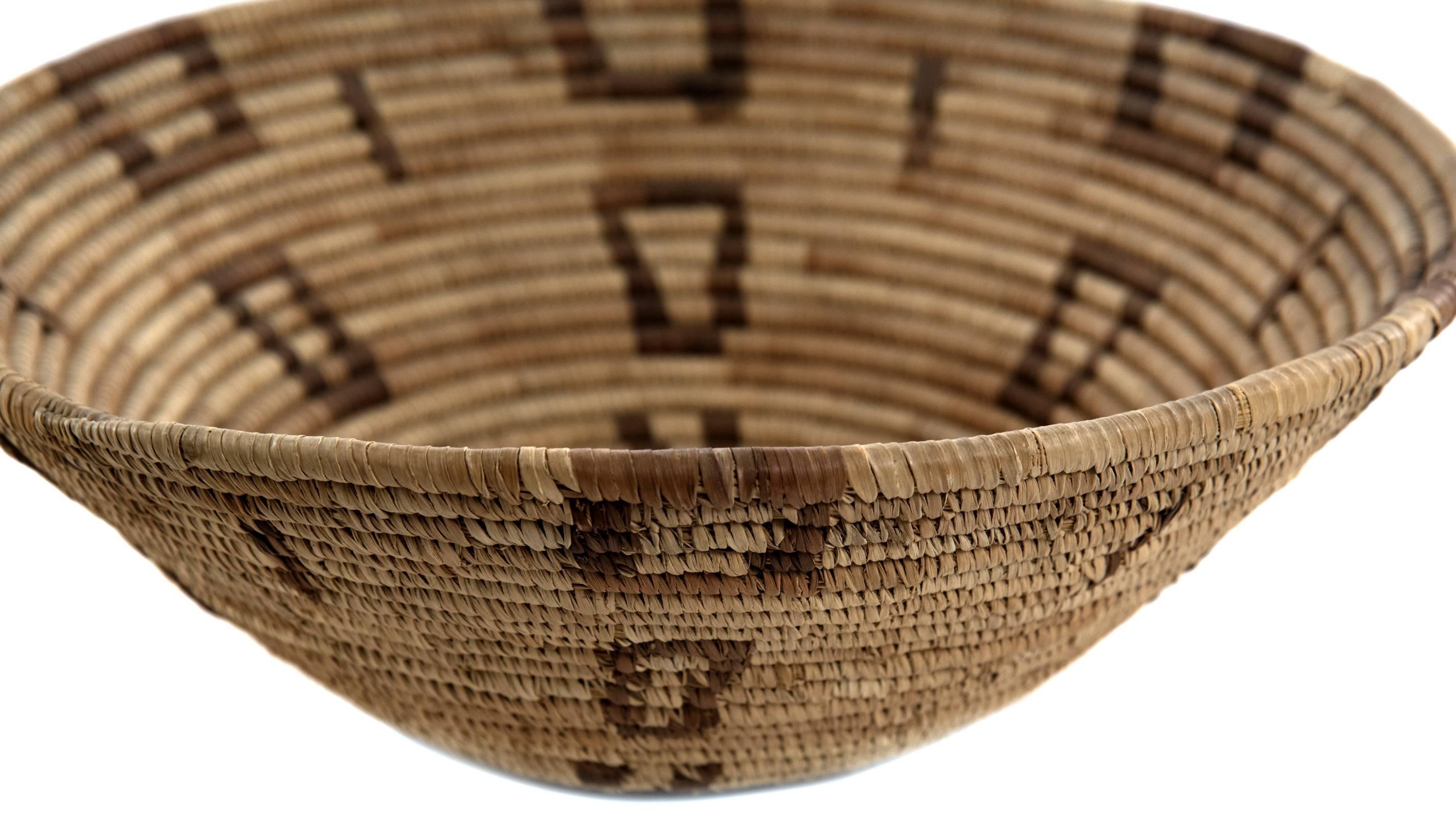 A 19th century Native American twined feast bowl with contrasting dark square motif that tapers to base with conical shape of bowl.