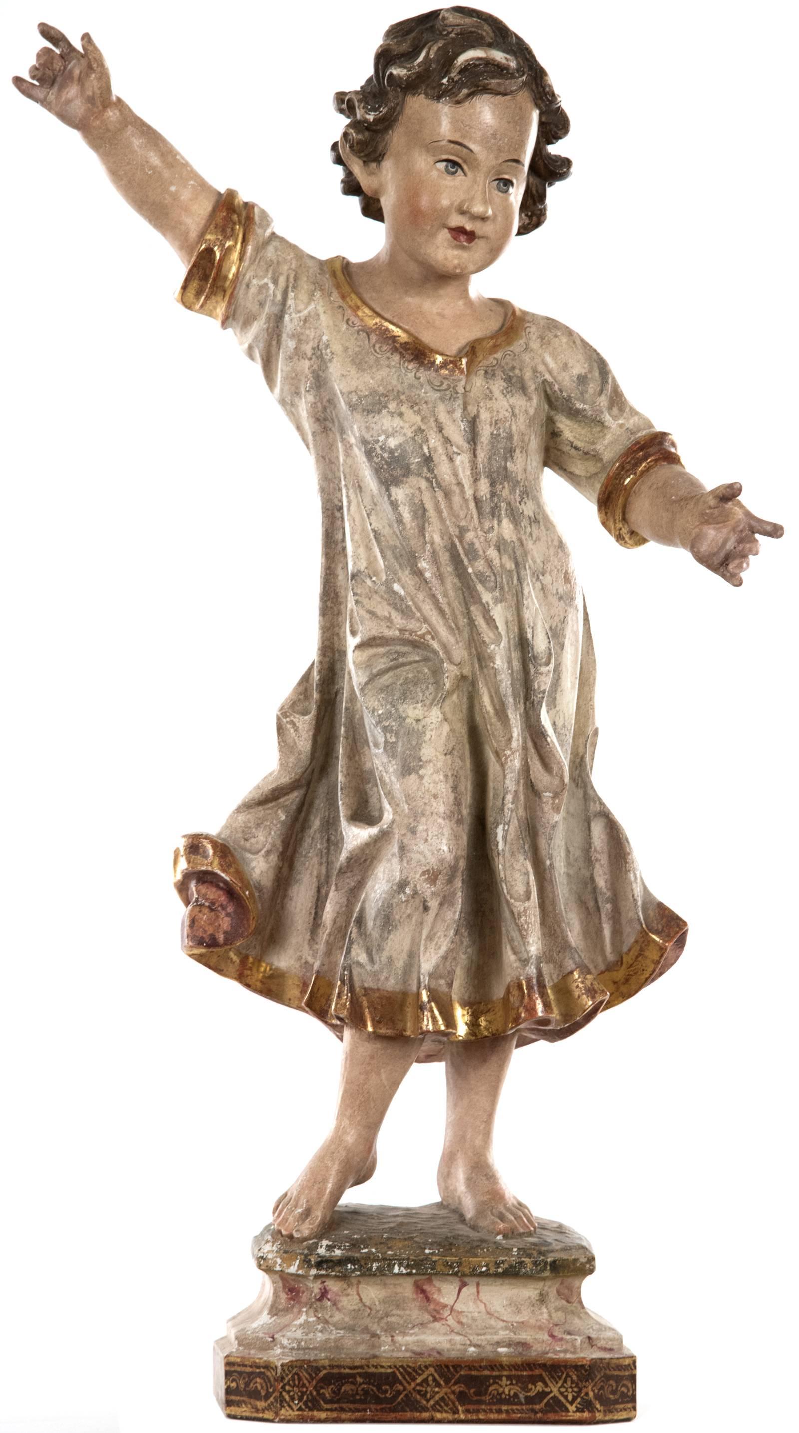 An ecclesiastical hand-carved and painted wooden figure of a young boy, his white and gold-trimmed robe flowing around his body with his arms stretched out as he is captured in mid-dance - a young boy full of energy and movement. The figure is