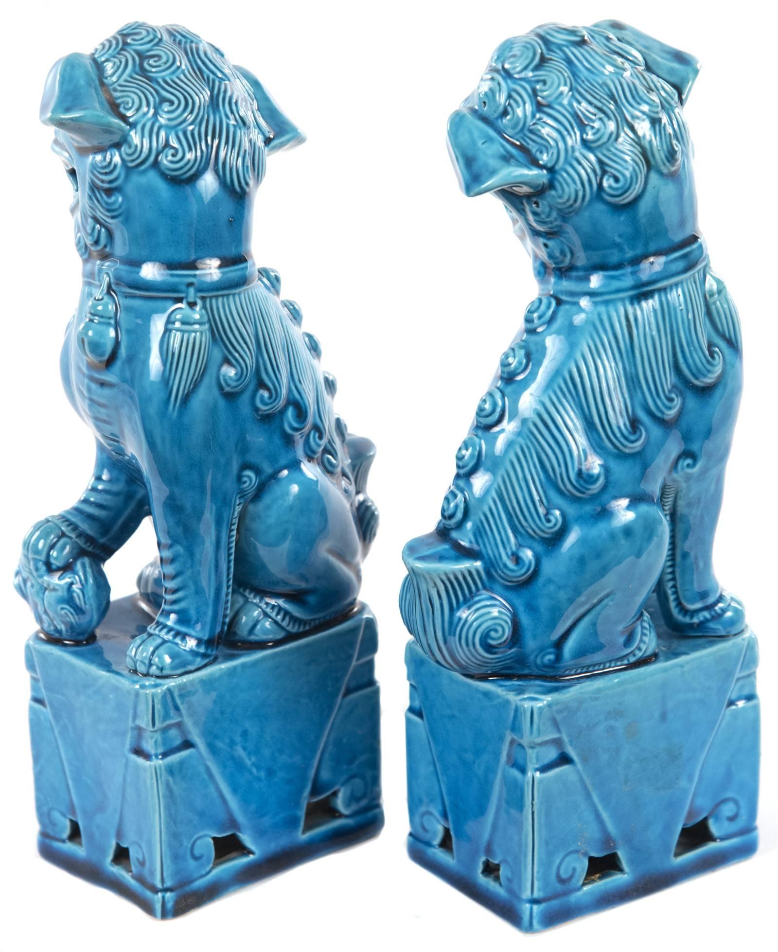 Each dog, and its square plinth, is covered in a rich lustrous turquoise glaze which darkens as it pools in the recesses, adding depth to the sculpture. Chinese Foo dogs are creatures with bodies that are comprised of half-lion, half-dog,