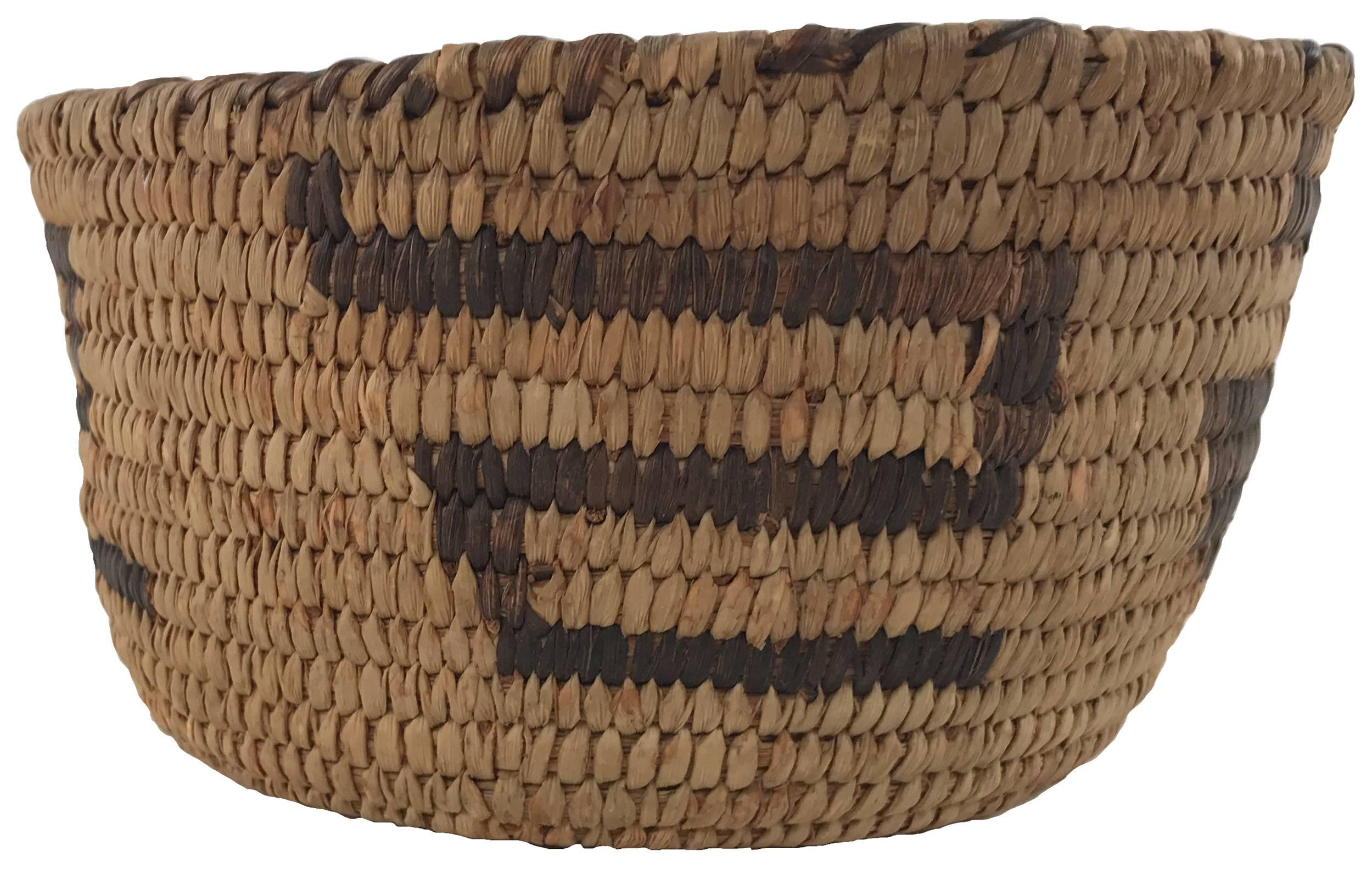 A small 19th century Native American twined woven bowl with contrasting dark snake or zig-zag motif around body of form.