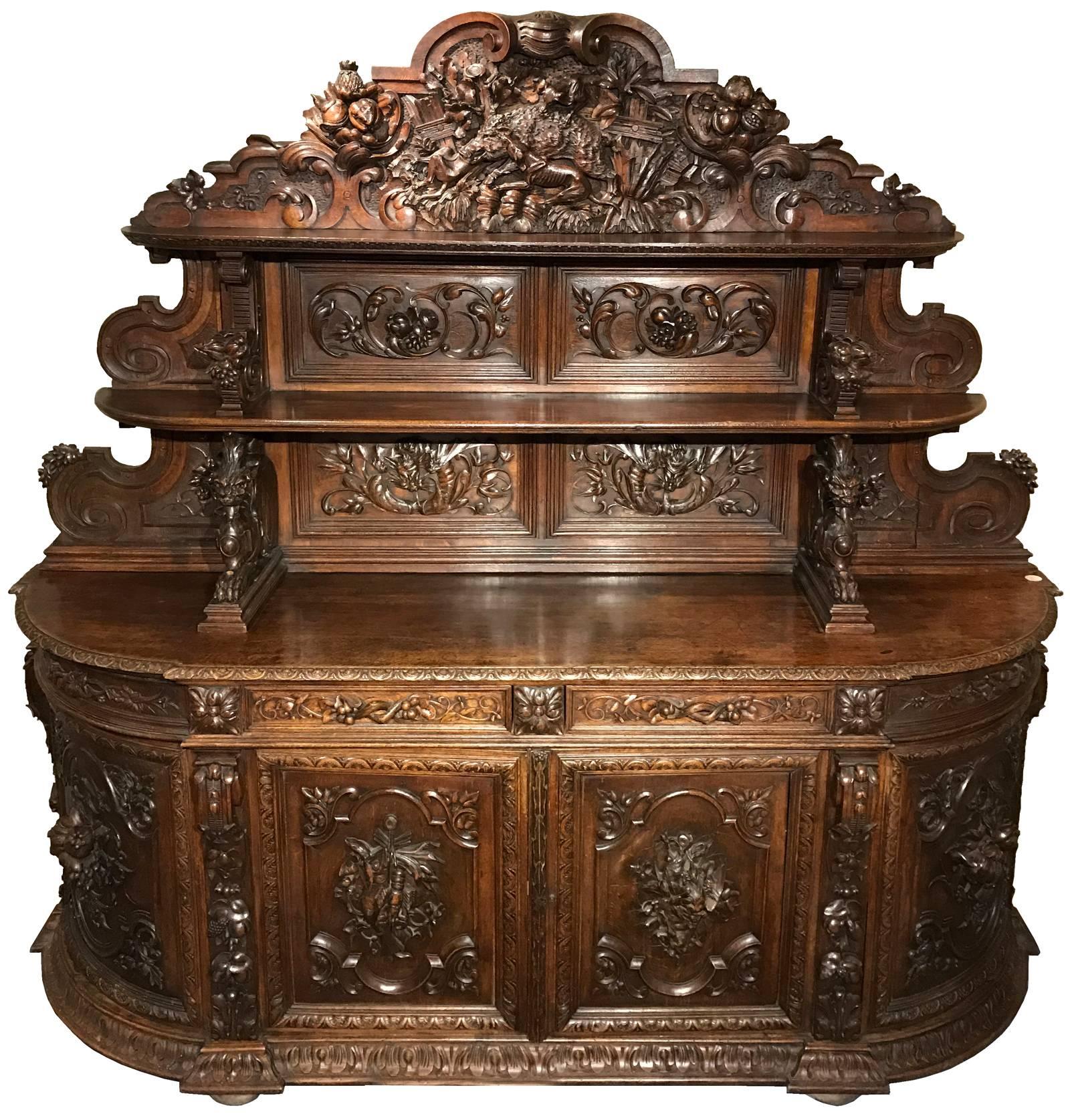 Un buffet massif magistralement sculpté à la main avec un fronton sculpté en forme de chasse au sanglier au-dessus de deux étagères ouvertes avec des supports de moisson et de griffon au-dessus d'une armoire à deux portes:: le tout recouvert de