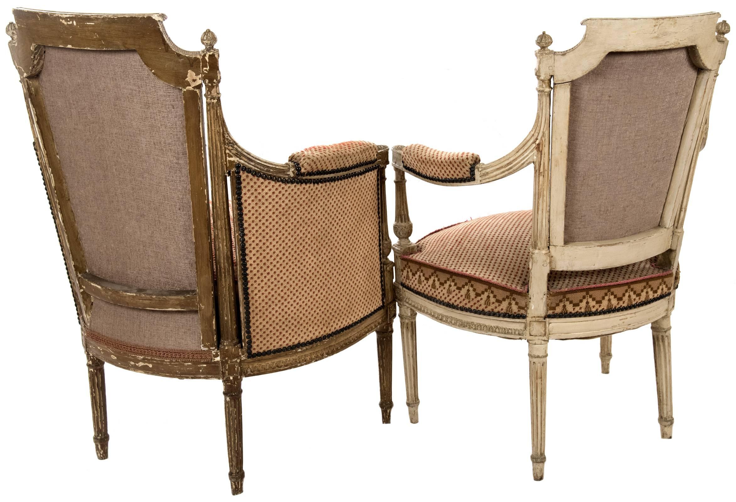 Two matching pairs of late 18th century Louis XVI armchairs with original, rich red and white silk upholstery. Both pair feature low-relief carvings of fluted columns, floral sprays, and acanthus leaves. One set is barrel shaped, with stuffed and