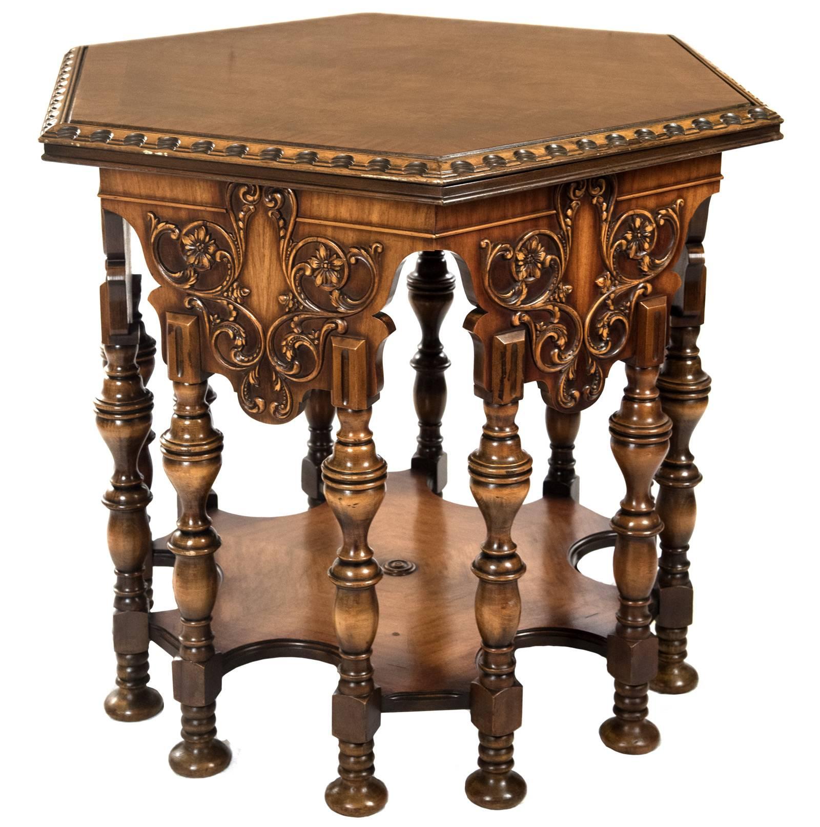 A side table of hexagon form with a banded burled top with scalloped stepped edges above floral carved aprons that are each supported by carved and turned sets of legs with bun feet and which are all joined by a six-edged scalloped shelf.