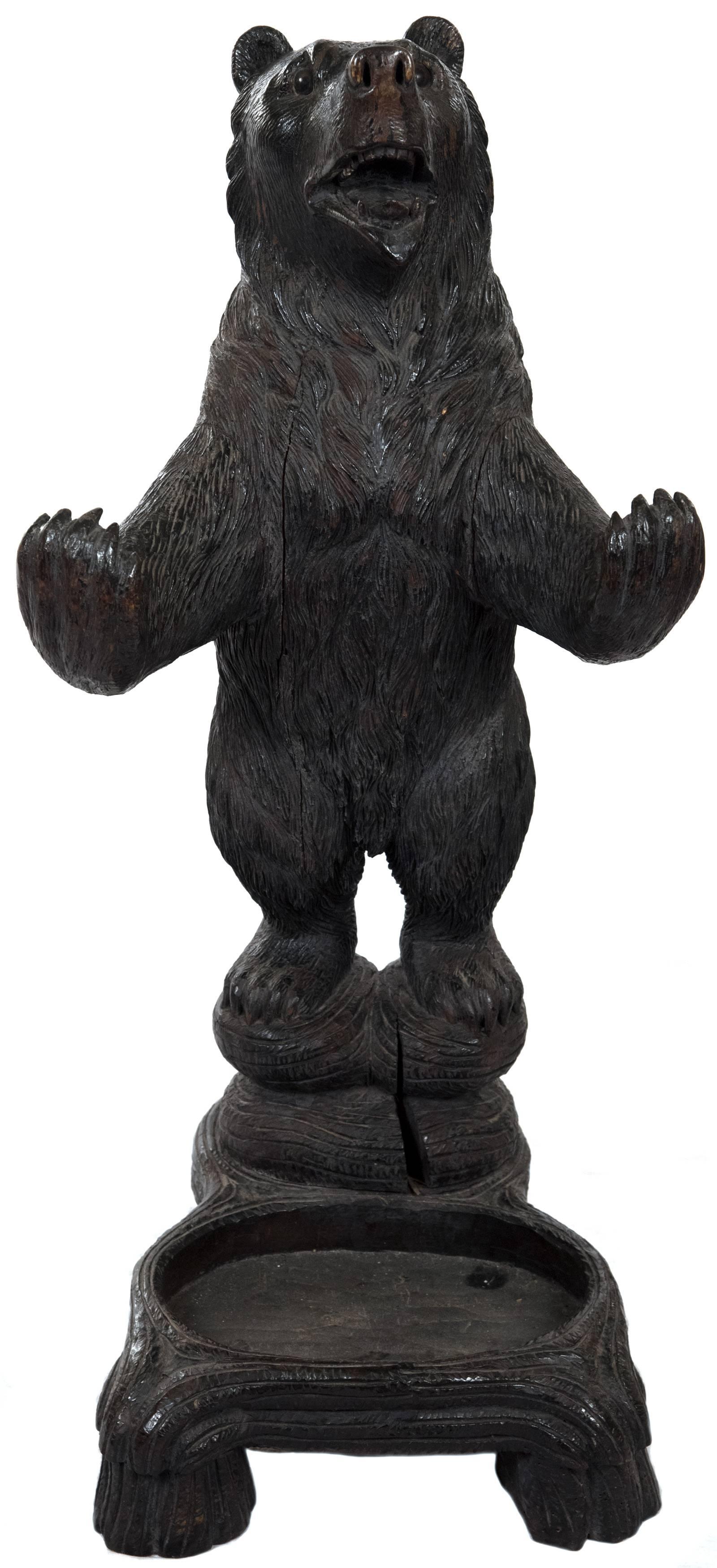 A very fine, carved linden wood Black Forest umbrella stand in the form of a bear carved in round with an open mouth and inset glass eyes. The base is carved with an integral drip pan.