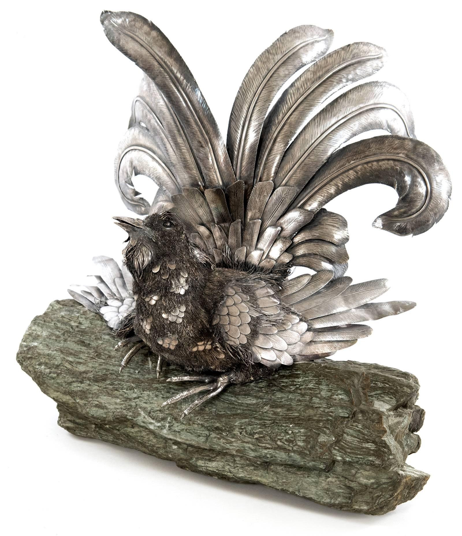 An Italian silver figure of a black grouse displaying its tail feathers while perched on a stone tree branch made in the mid-twentieth century by Italian jewelry house Buccellati. The form is realistically modeled as a wirework fighting cock with
