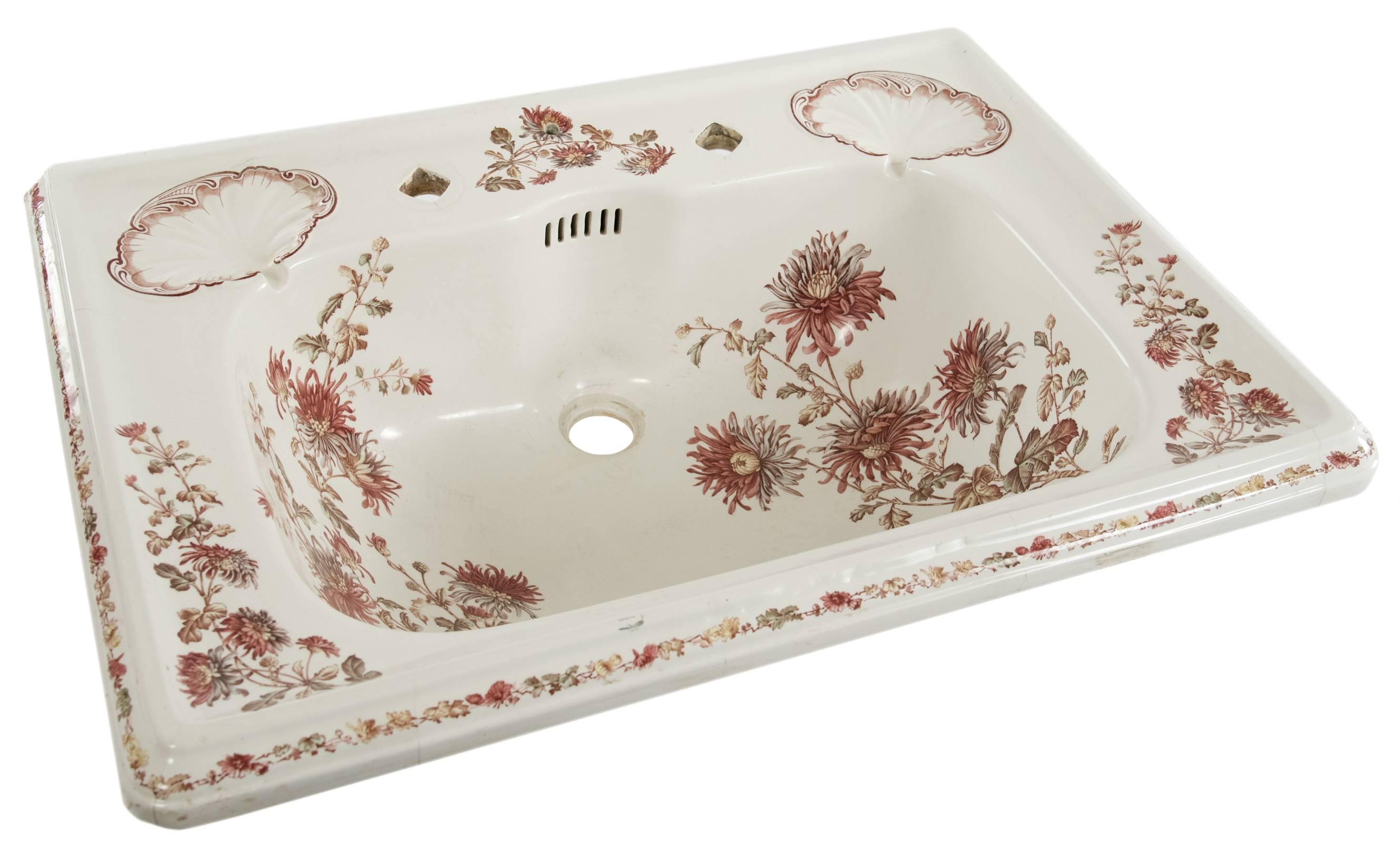 A Victorian porcelain basin with an under glaze polychromatic transfer design of garland and florals, the rectangular edges trimmed in a chain of small flowers. There are two soap dishes with raised detail above the oval bowl. The sink is drilled