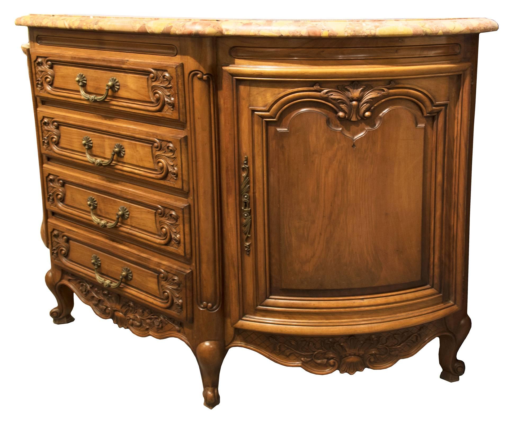 A handsome demilune chest of drawers with a yellow marble top with a molded edge, above a frieze with carved elliptical forms. Four stacked drawers with carved scroll and foliate fronts on a quilted ground and centred brass pulls are flanked on each