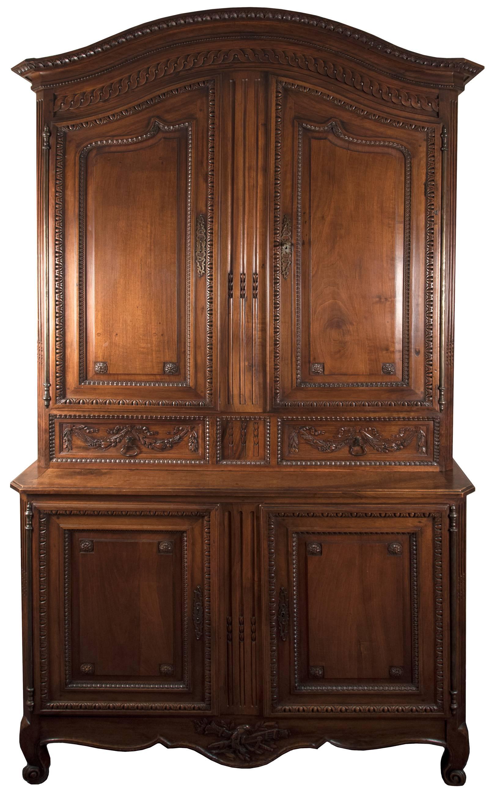 A magnificent 18th century armoire with an 'en chapeau', or curved central pediment with a deep steeped out molding, which sits above a frieze carved with beaded and guilloche pattern. The centre dormant panels of both the upper and lower case is