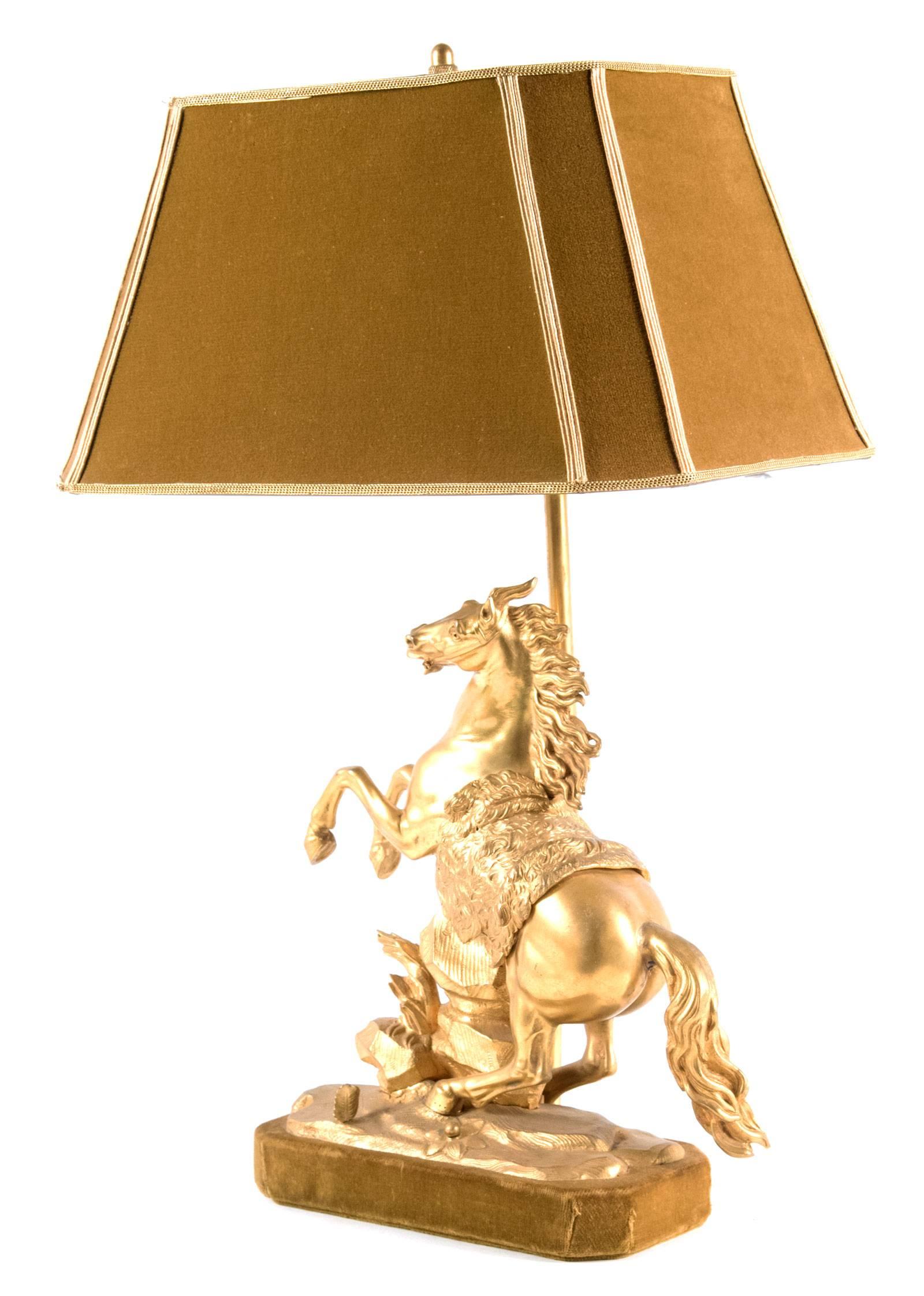 A large gilt bronze Marly horse table lamp after those created by Guillaume Coustou. The powerful creature rears on its hind legs, a wild look captured is in eyes. The details of the mane, riding blanket and naturalistic base have been finely