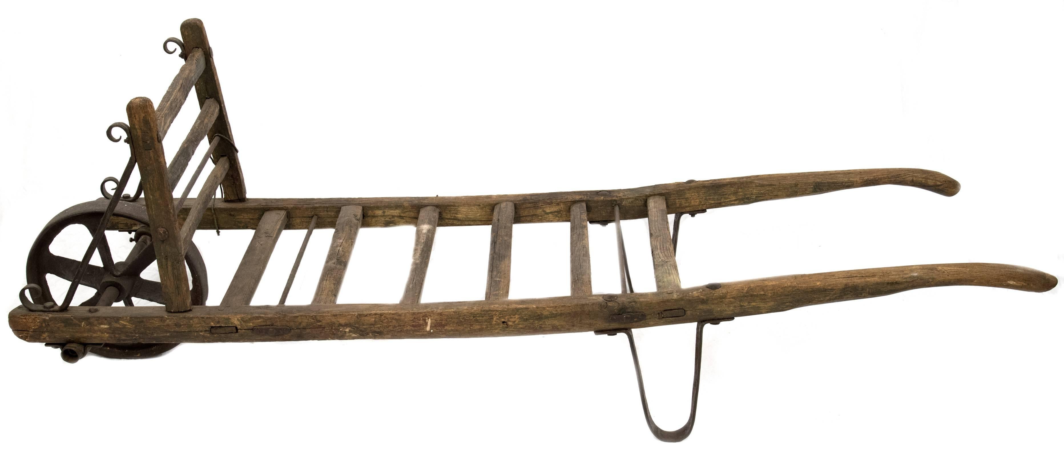 A walnut and cast iron hand truck made in France during the fourth quarter of the 19th century and used for the transportation of oak wine barrels.