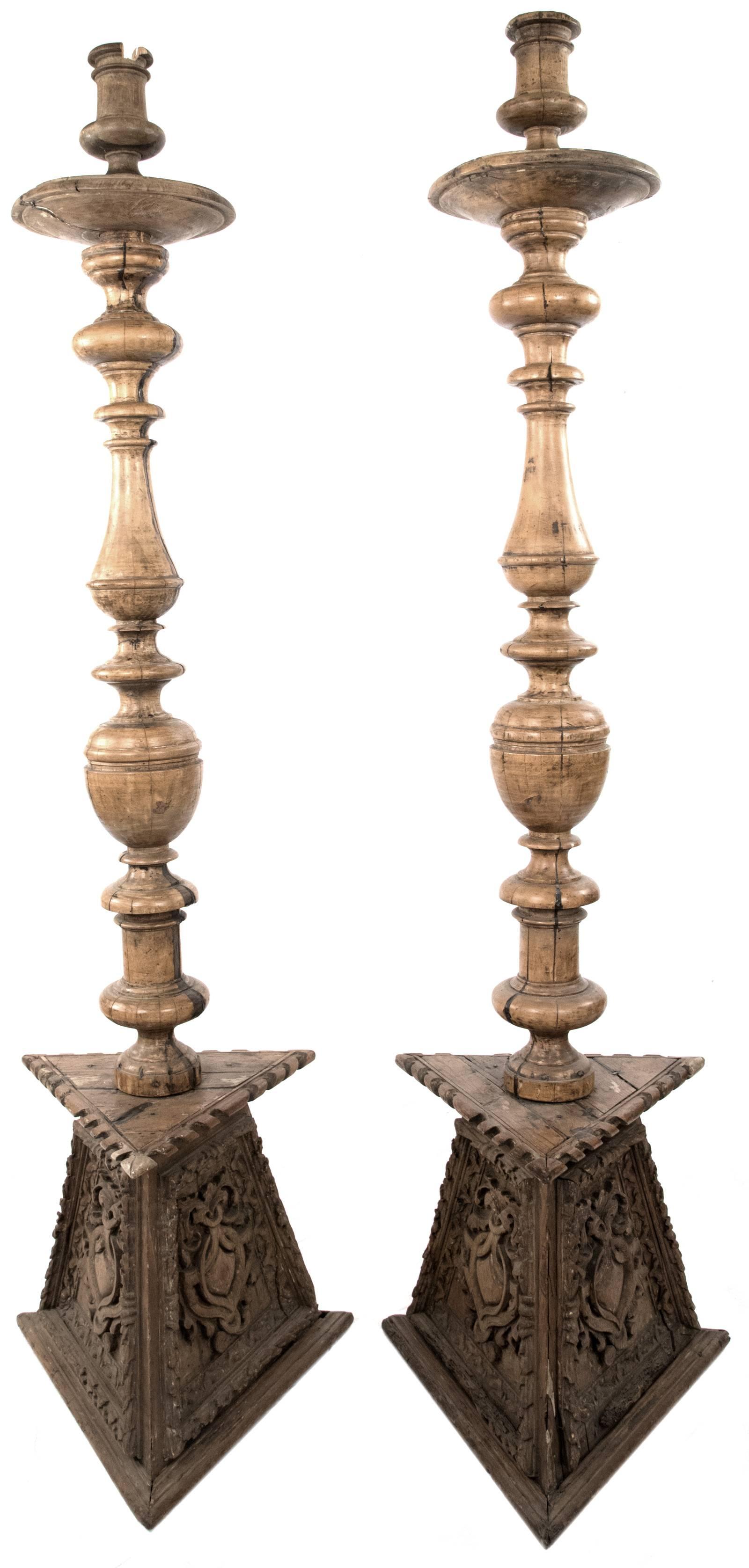 Two 18th century carved and turned fruitwood candelabras, made in Northern Italy. The sides of the three-sided bases are carved with crests surrounded by acanthus leaves and decorative dental work. The stems are made from thick and beautifully aged