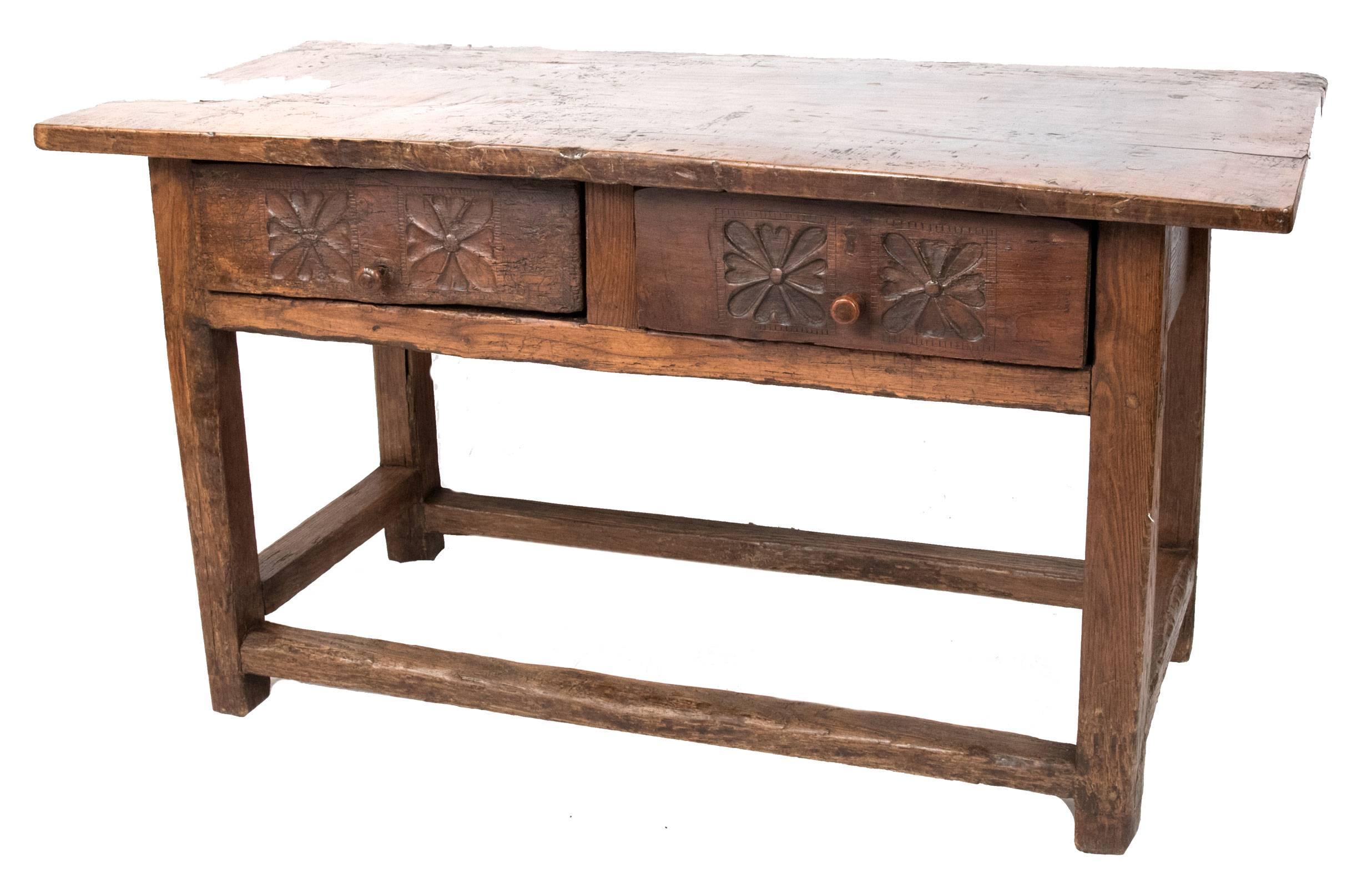 A 19th century walnut console table with a slab top above a frieze with two drawers. One drawer looks original, the front decorated with carved floral motifs and incised with additional decoration and a single pull, while the second is decorated