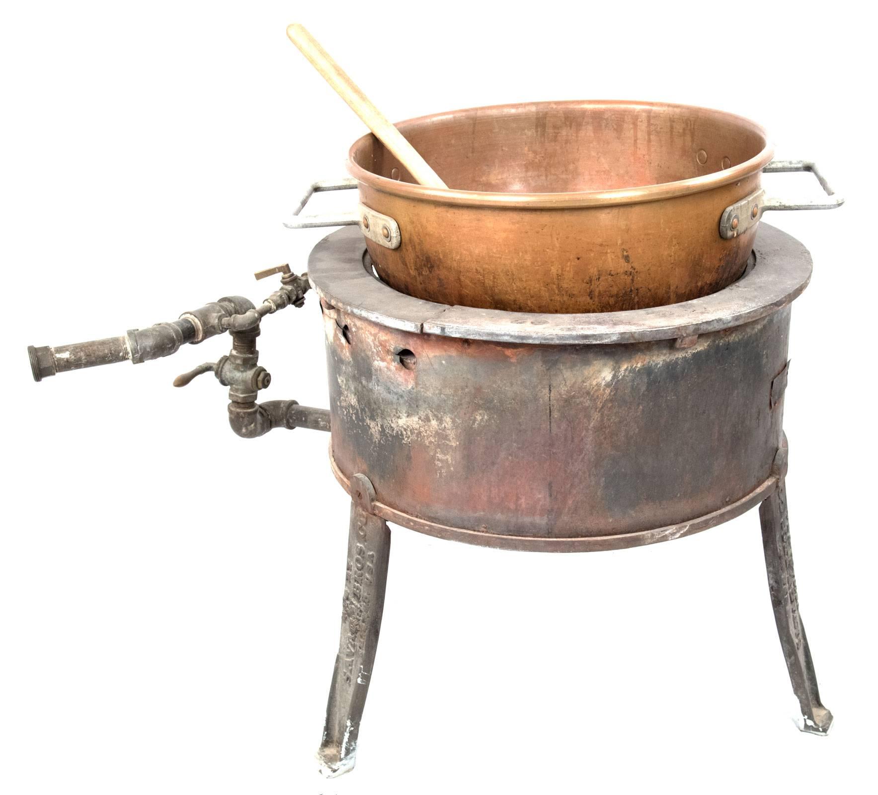 A large candy-making copper bowl with steel handles, fitted within a gas burner, made by the American company, Savage Bros. Co., which was established in 1855.