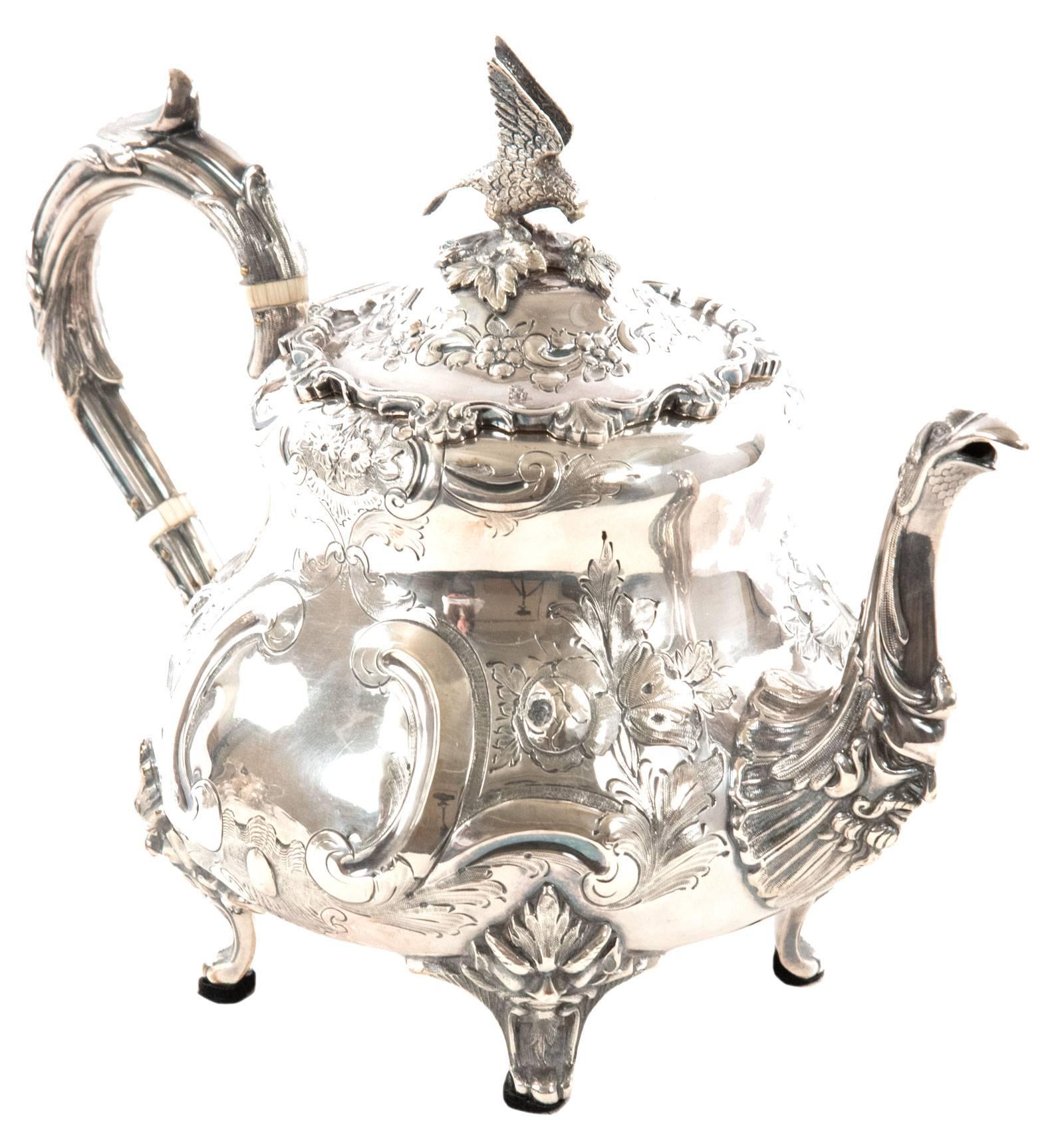 A Victorian English silver plate tea service with tea pot, sugar bowl and milk jug, of baluster form and ornately decorated in the Louis style. The lower portion of the body is embellished with chased scroll, floral and leaf decoration on a scale