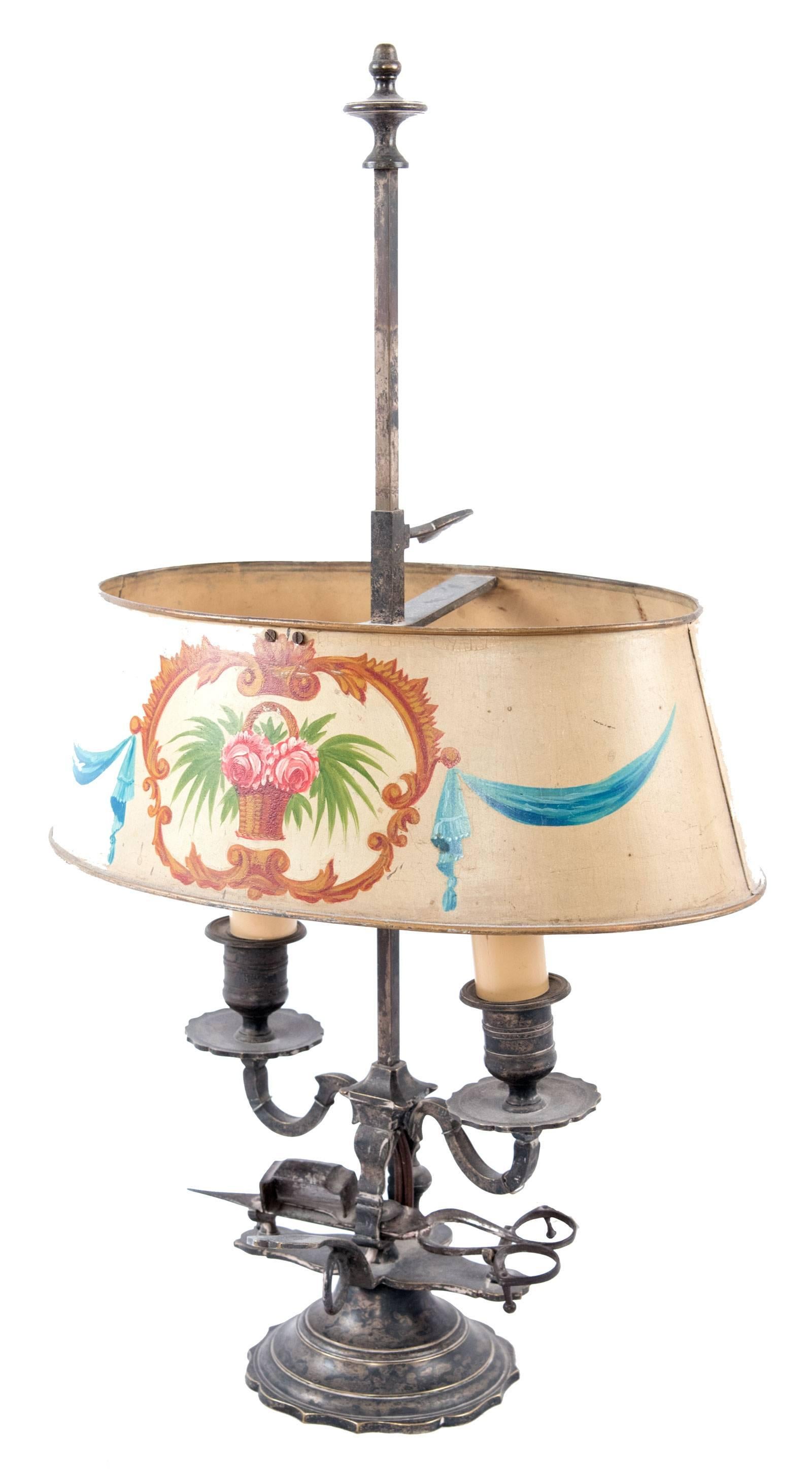 Wired for modern use, this two-light table lamp of plated silver was made during the last quarter of the 19th century and features a painted metal toile lampshade and silver scissor candle snuffer. Dimensions: 21 x 12 x 8 in.