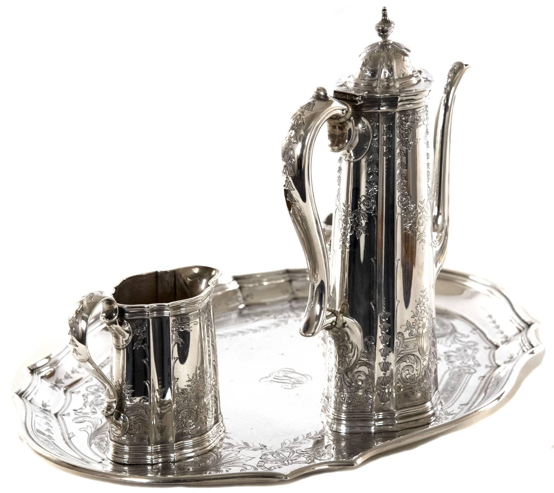 An early 20th century, circa 1092-1907, four-piece Tiffany & Co. sterling silver coffee service comprised of a scalloped edge serving tray, coffeepot, creamer and sugar bowl. The elongated and panelled body of each piece is hand-hammered and chased