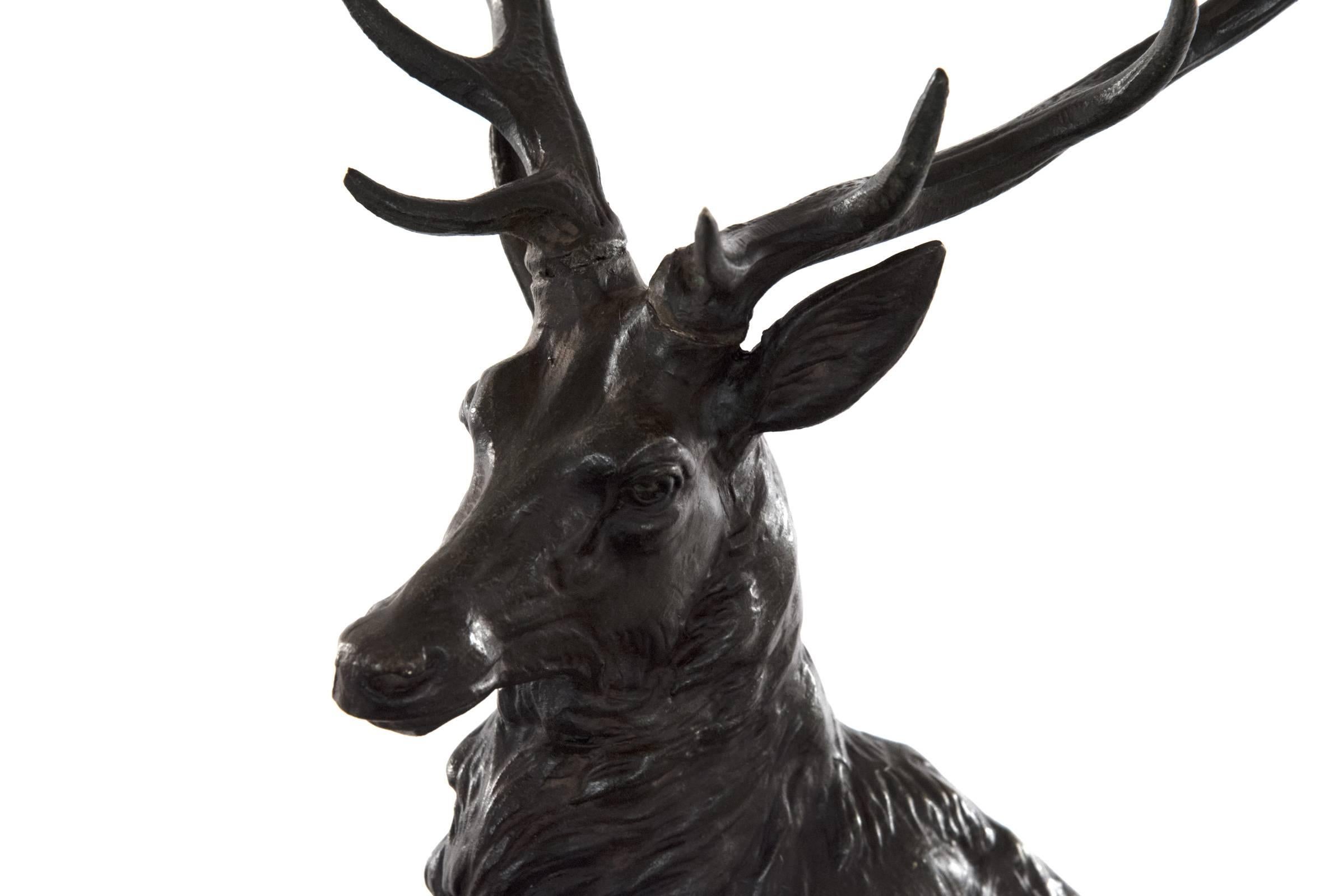A bronze sculpture of a stag and doe affixed to an illuminating naturalized glass base that is mounted to a variegated black marble plinth. The finely cast animal forms are after French animalier sculptor Louis-Albert Carvin (1875-1951). Measures: