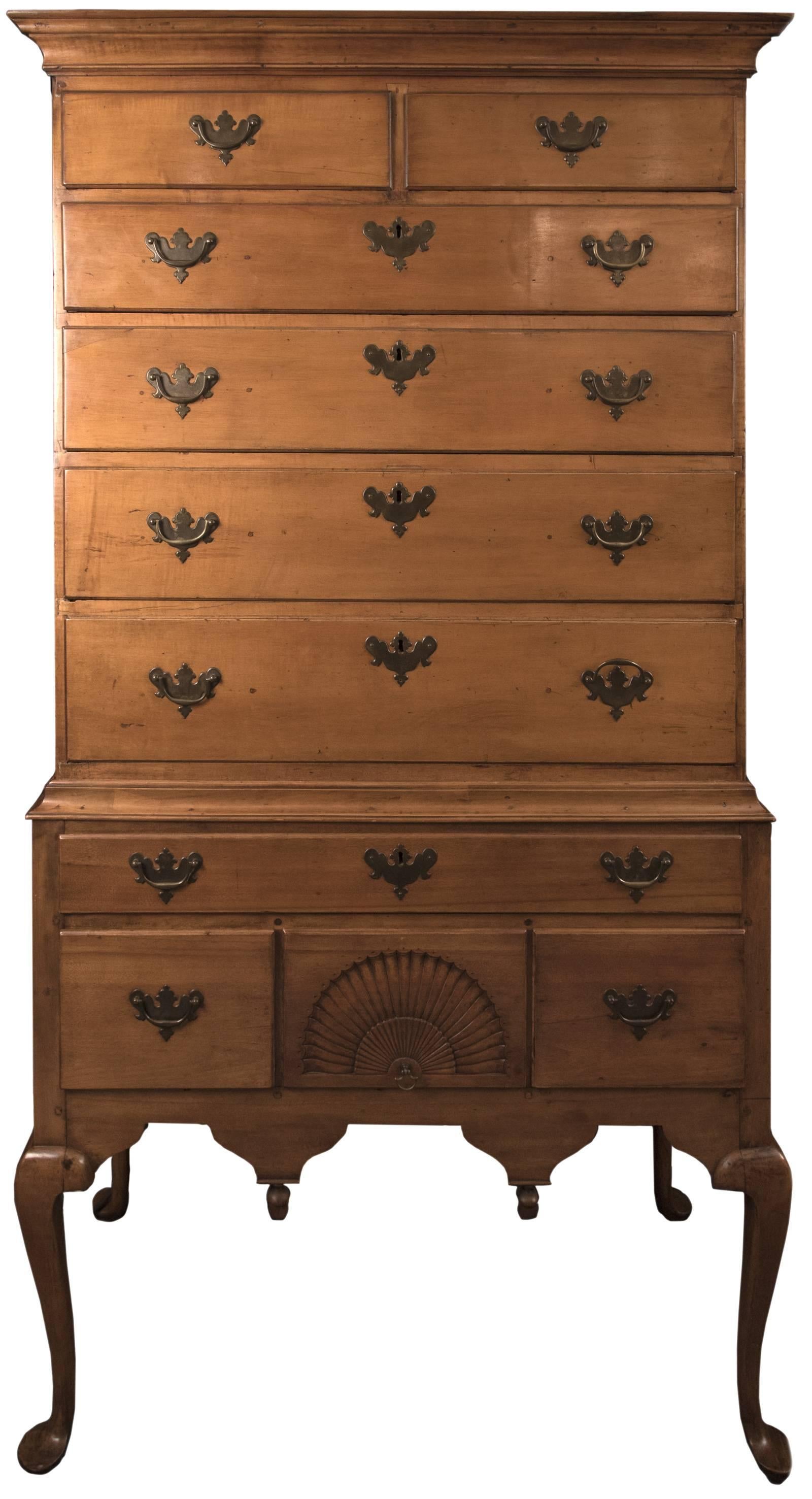 A carved maple two-piece highboy with a flat cornice top over a chest of two short drawers over five graduated long drawers. The base displays a chest with a single long drawer over three larger drawers, the centre with a carved fan design. All
