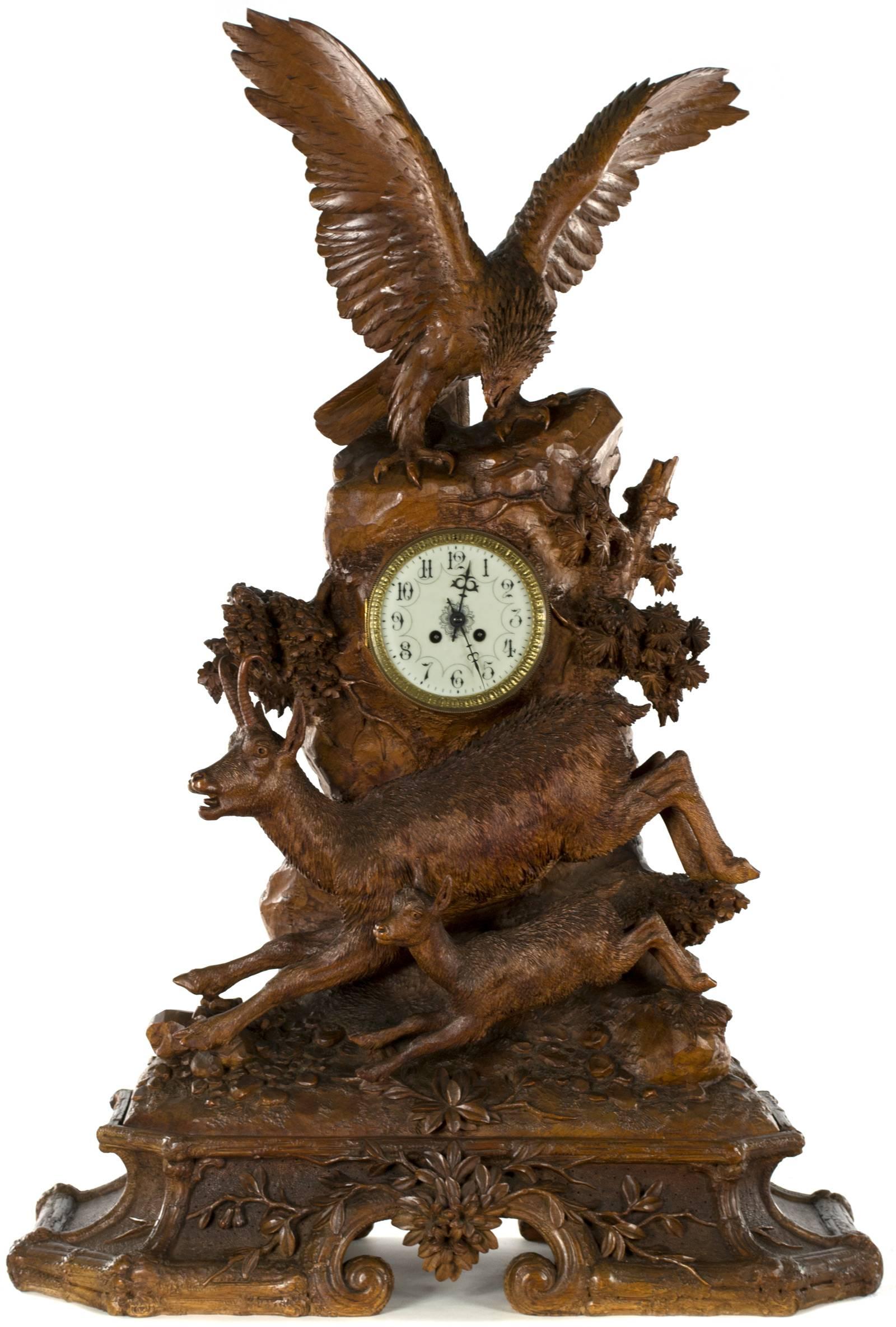 A very fine, large linden wood Black Forest mantel clock with a carved figural group of two full-relief jumping chamois below the clock face, which itself is surmounted by a large eagle, with its wings spread the width of the clock. The fine quality