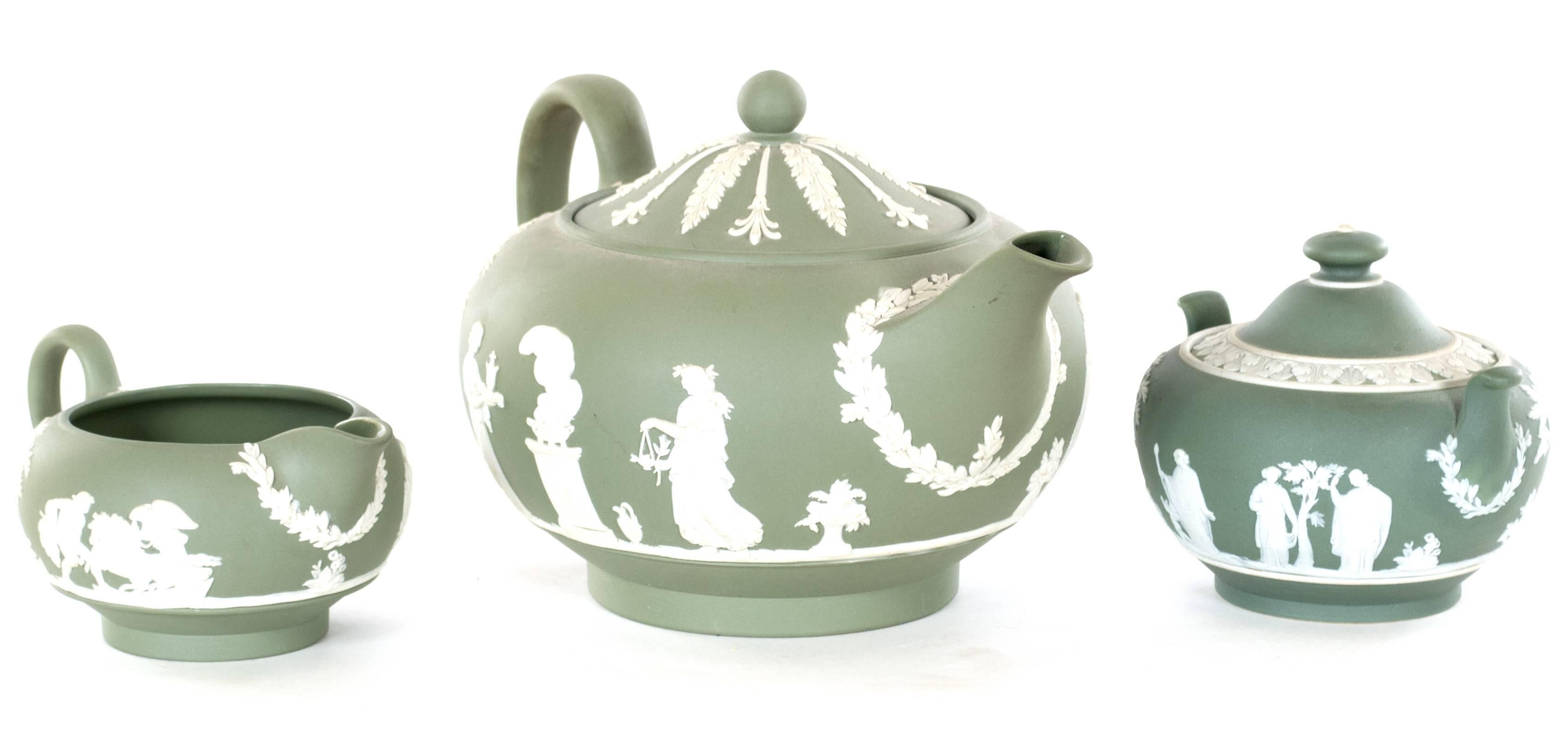 A matching set, including a teapot, sugar bowl, and creamer in the iconic jasperware green porcelain bisque with white, classical figures. The base of each is stamped 