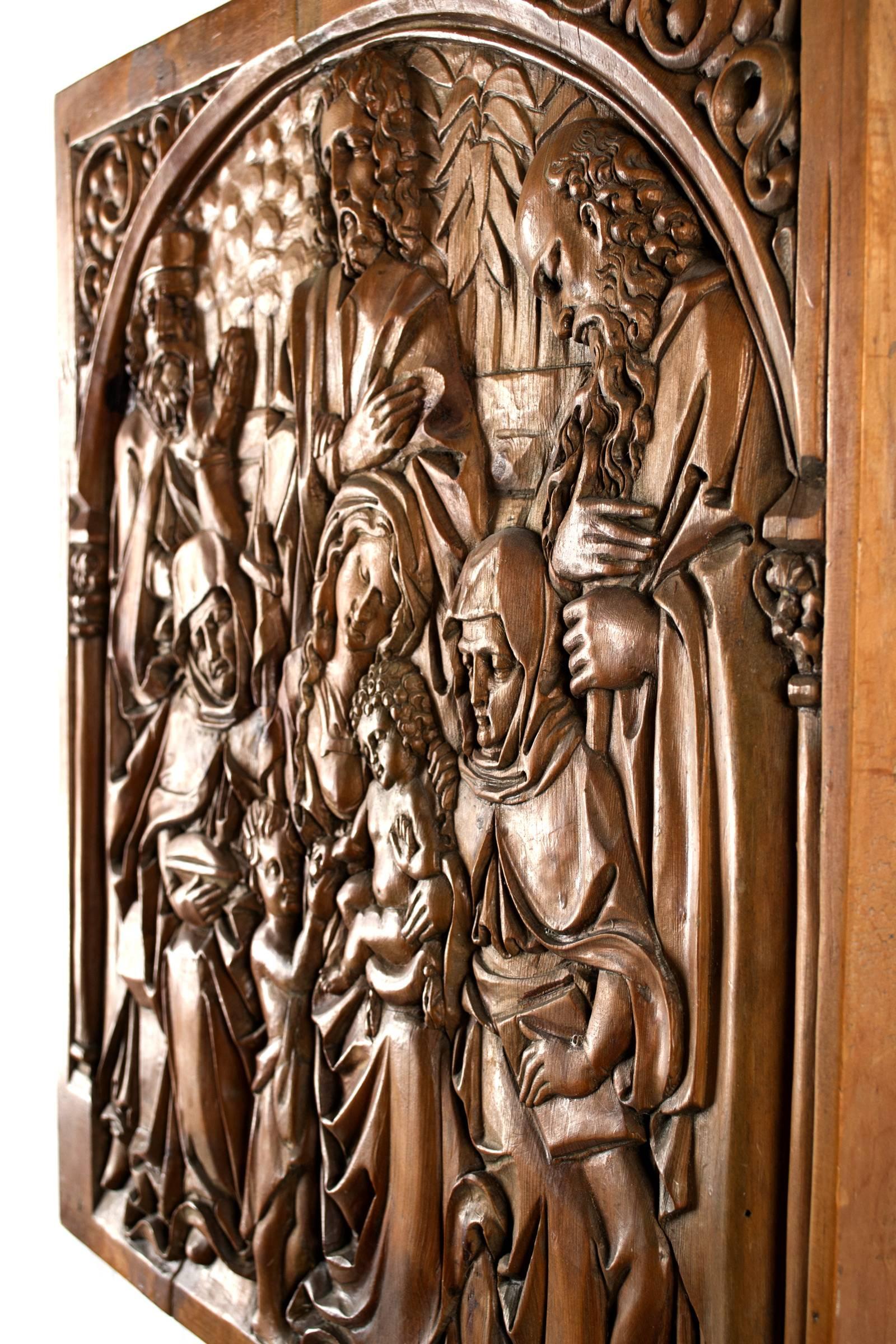 A low-relief sculpture plaque of the Holy Family, Mary sits in the center with the Christ child on her lap and Anne (i.e. Mary's mother) and Elizabeth (i.e. her cousin) on either side together with their husbands. Joseph stands behind as the young