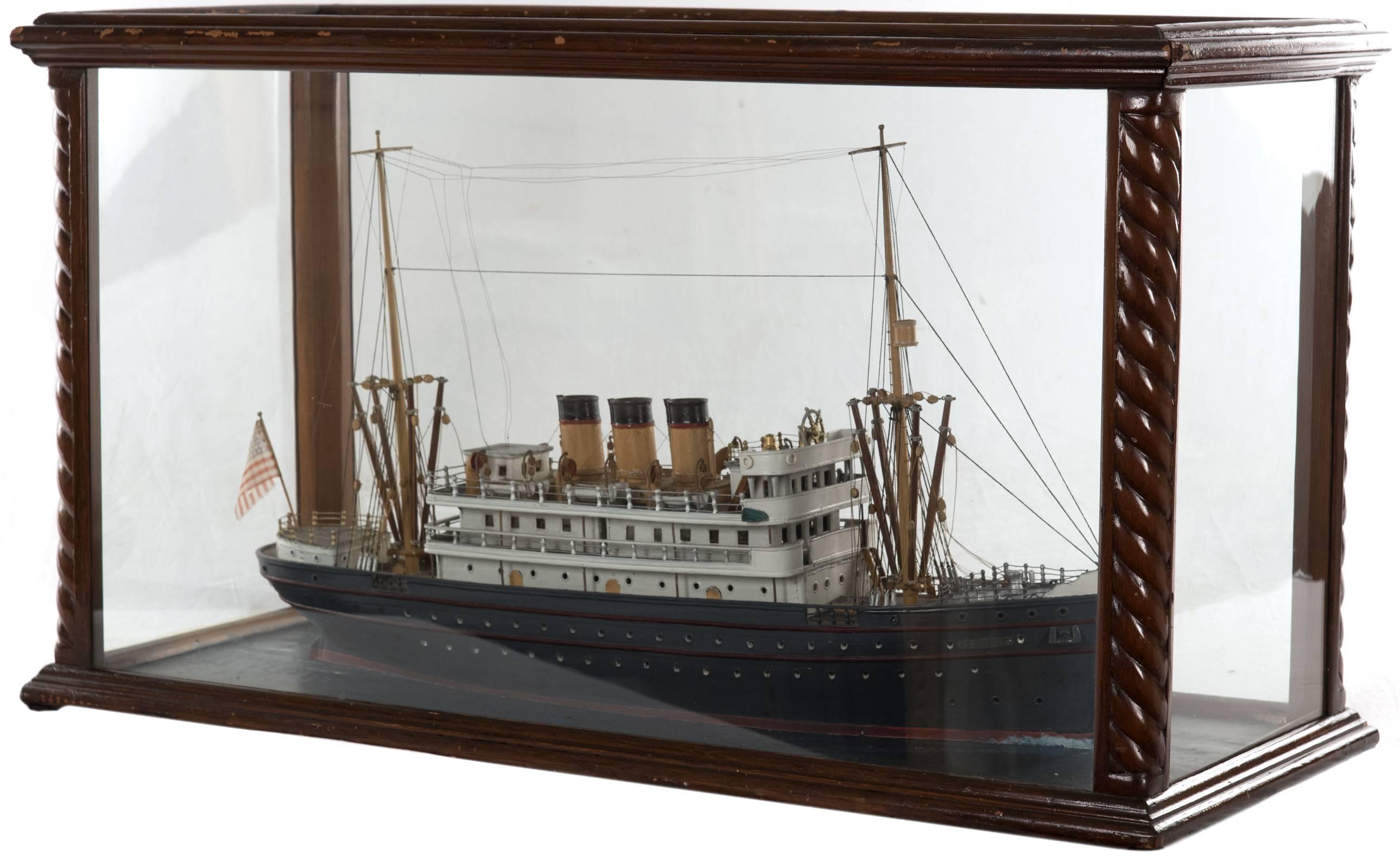 Carved and painted wooden model of American steamship, Neptune, with a blue and red painted hull and detailed rigging, two-masts and three steam stacks and American flag mounted on stern, housed in a custom built glass display case with turned wood