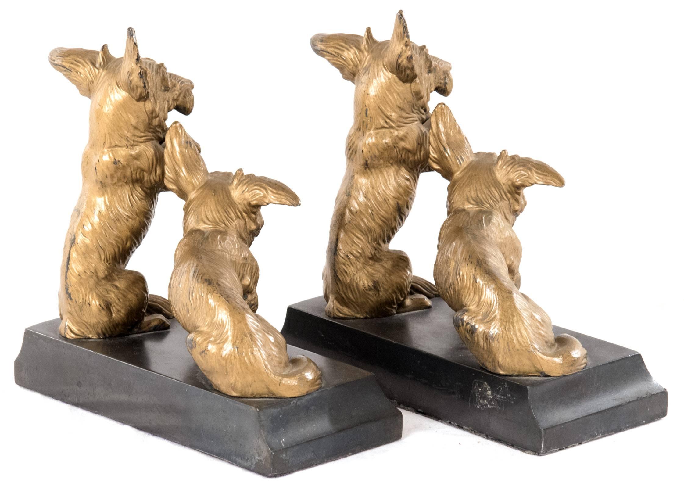 A set of bookends, mirroring each other, with a pair of Welsh Corgi dogs mounted on a black marble base, one sitting and the other raised on its hind legs, begging.