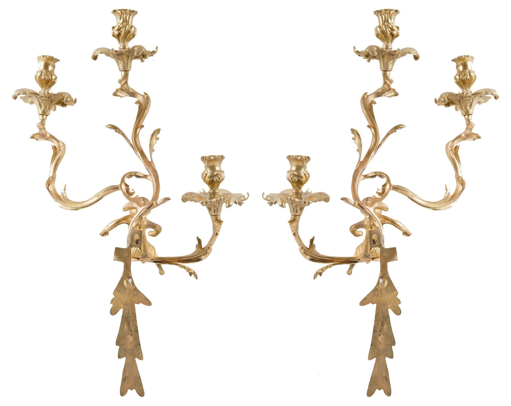 A pair of Louis XV-style gilt wall sconces with three scrolling foliate arms supporting thistle-form sockets, with chased hanging tendrils, and mounted with the figure of a centaur.
