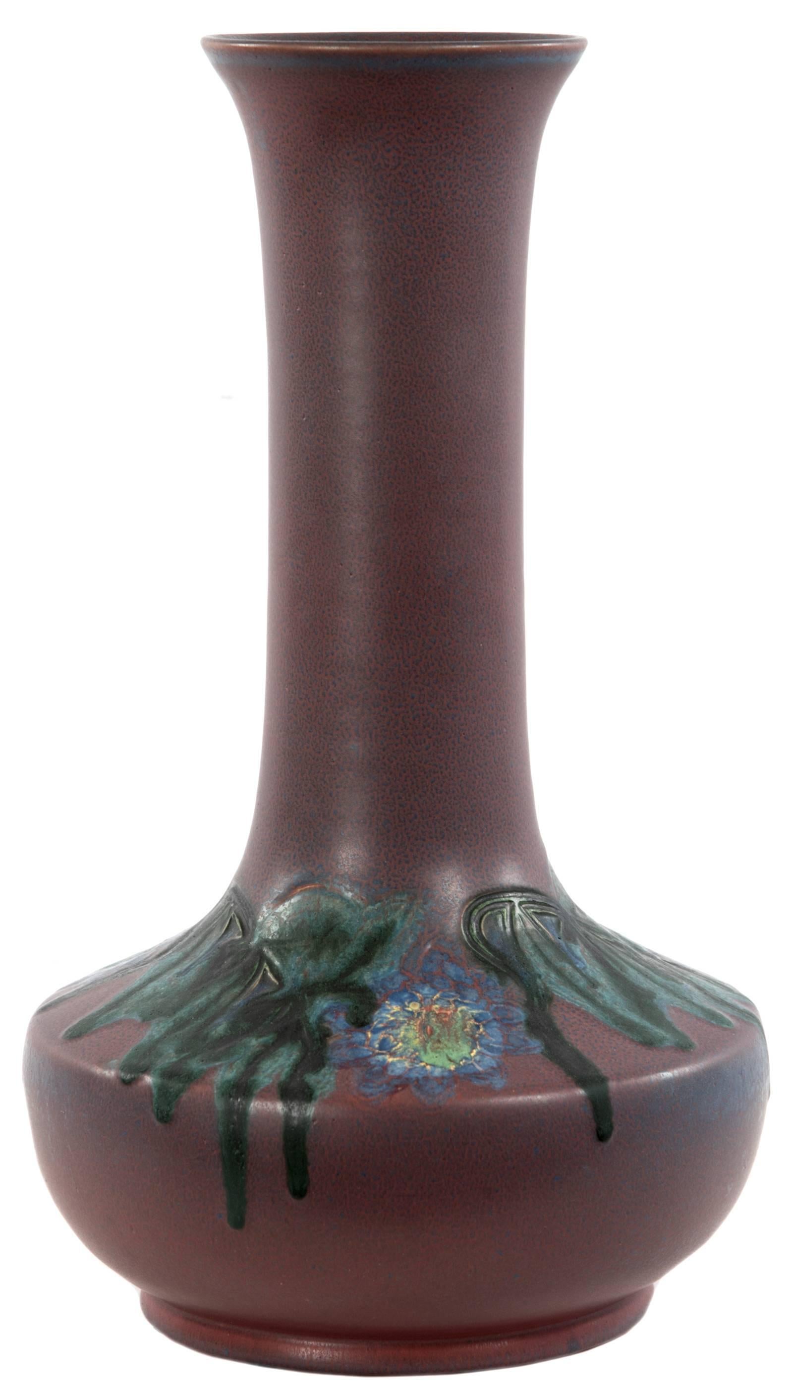 Charles Todd (American, 1886-1950) Rookwood pottery vase with crazing matte-purple glaze decorating a flared lip surmounting a long and narrow neck that swells to angular shoulders, which are detailed with carved and painted blue florals and deep