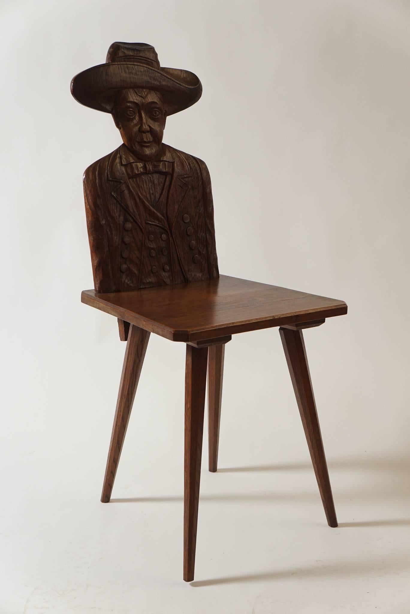 A truly wonderful and unique pair of French, circa 1920, hall seats or back stools of chestnut construction having carved full upper-body portrait backs depicting different 'Western' attired gentlemen, connecting trapezoidal shaped flat seats with