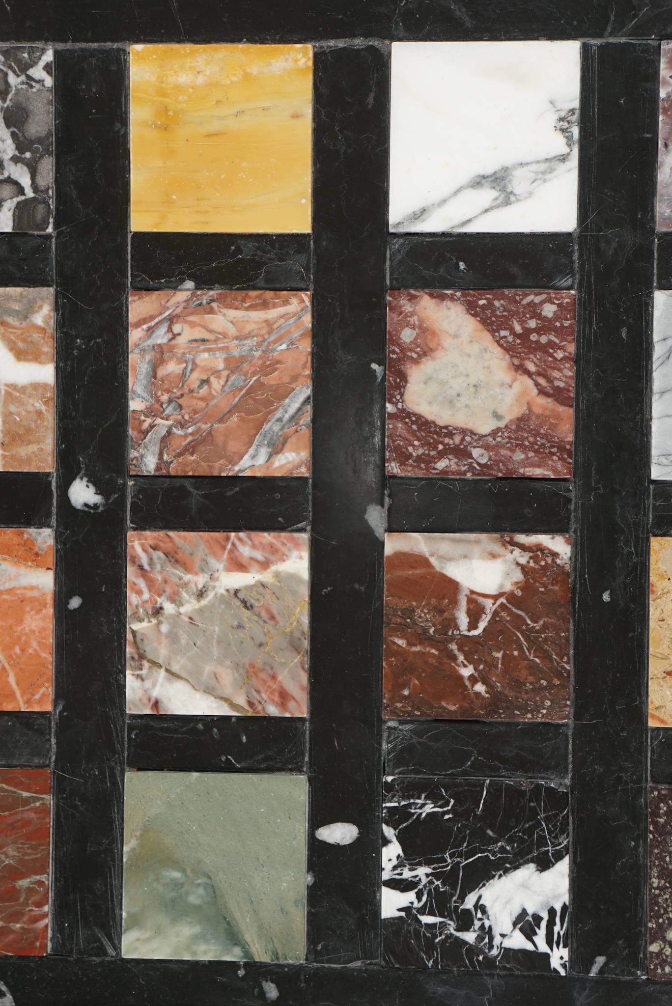 Italian Grand Tour marble specimen plaque in original silver-giltwood frame consisting of 20 different rare and ancient marbles, including Porphyry and Jasper, inlaid into a black and white onyx geometric grid.