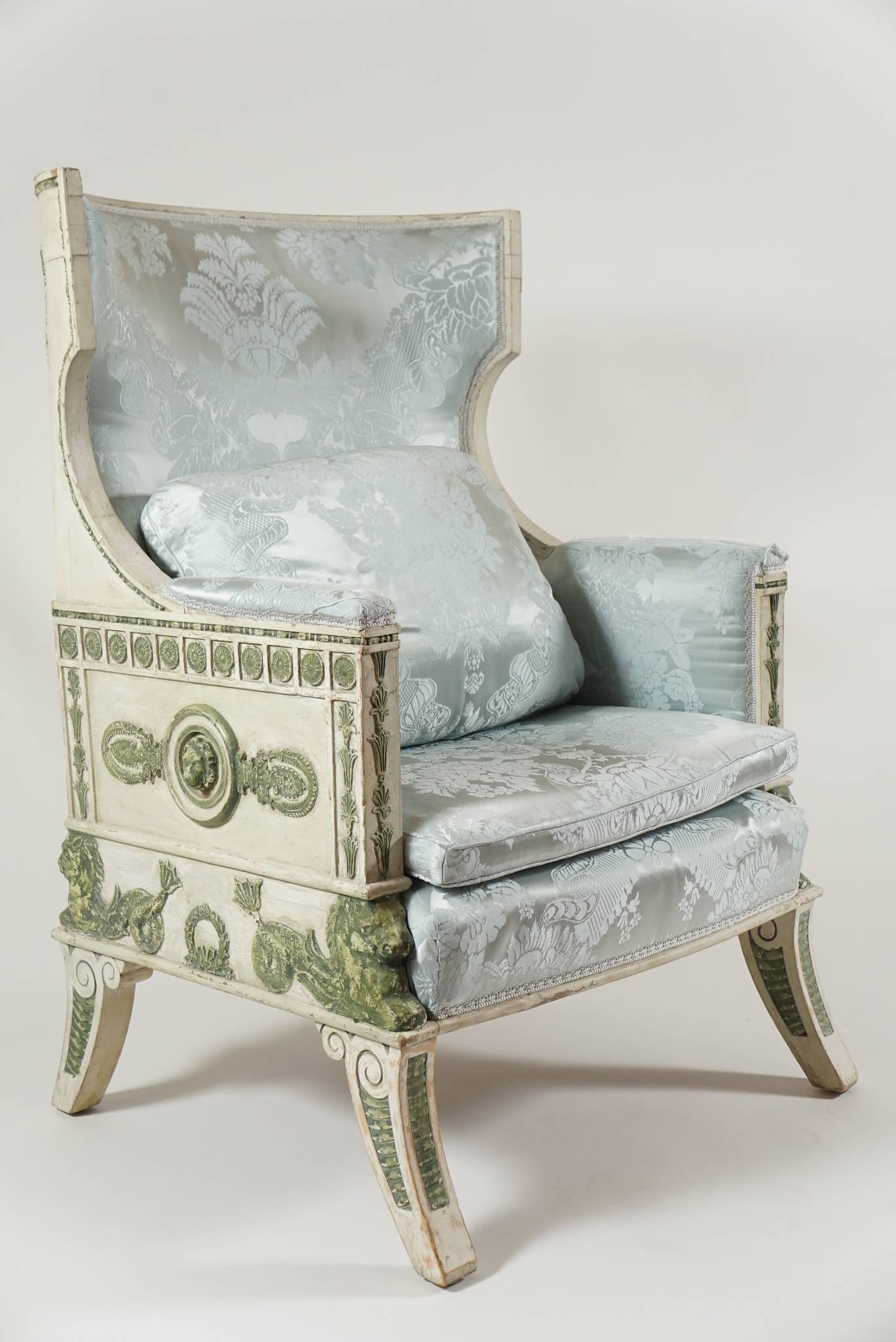 A rare, exceptional, and visually dynamic Baltic Empire style bergere of neoclassical form having polychrome painted carved wood frame with klismos form upholstered 'wing' backrest, armrests, interior-sides, squab cushion, and seat, and all-around