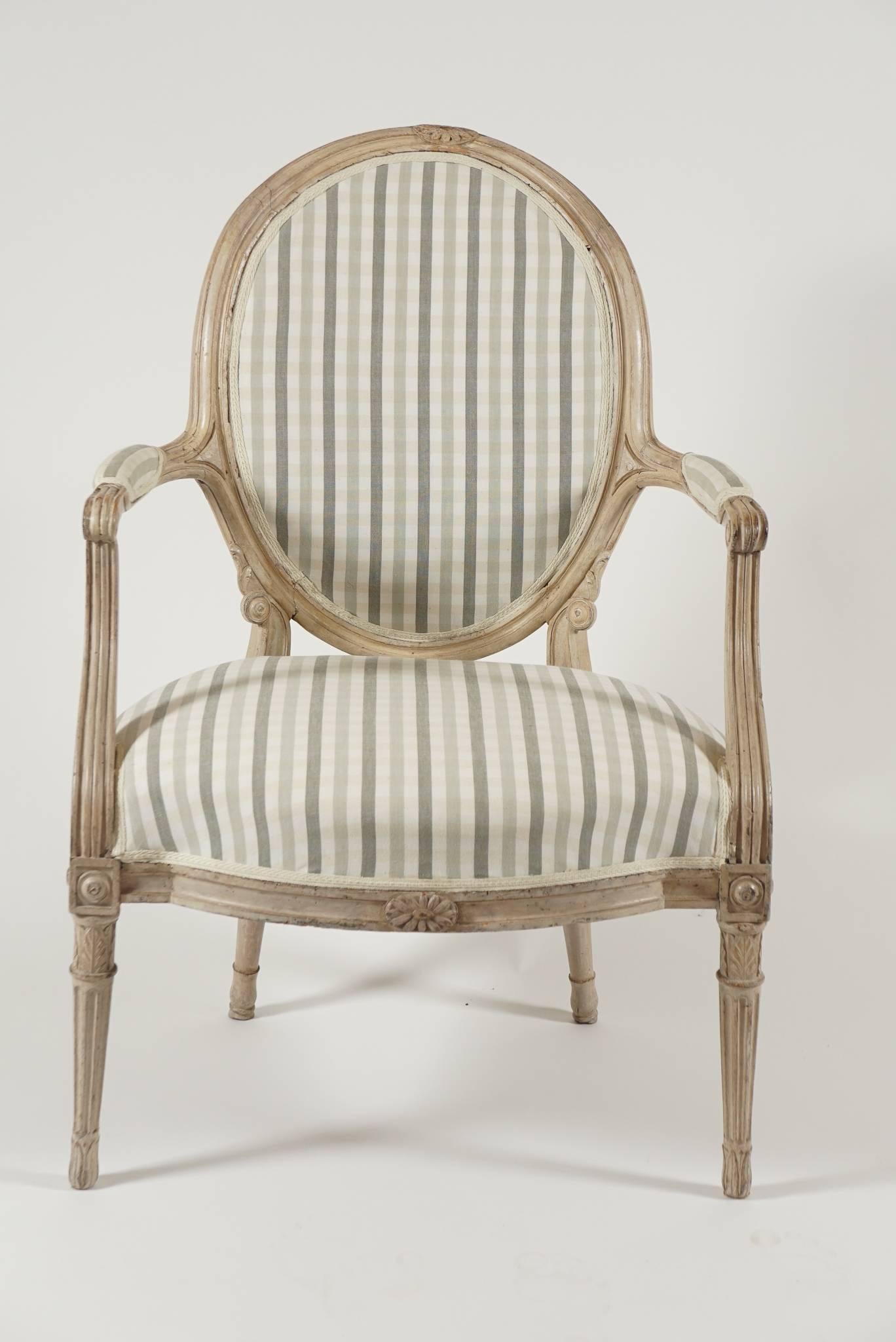 An elegant circa 1790, Danish, Louis XVI style fauteuil with carved wood frame having exceptional detail and original painted finish with upholstered oval-shaped backrest, armrests, and seat.  The design of this chair references a c. 1770 chair by