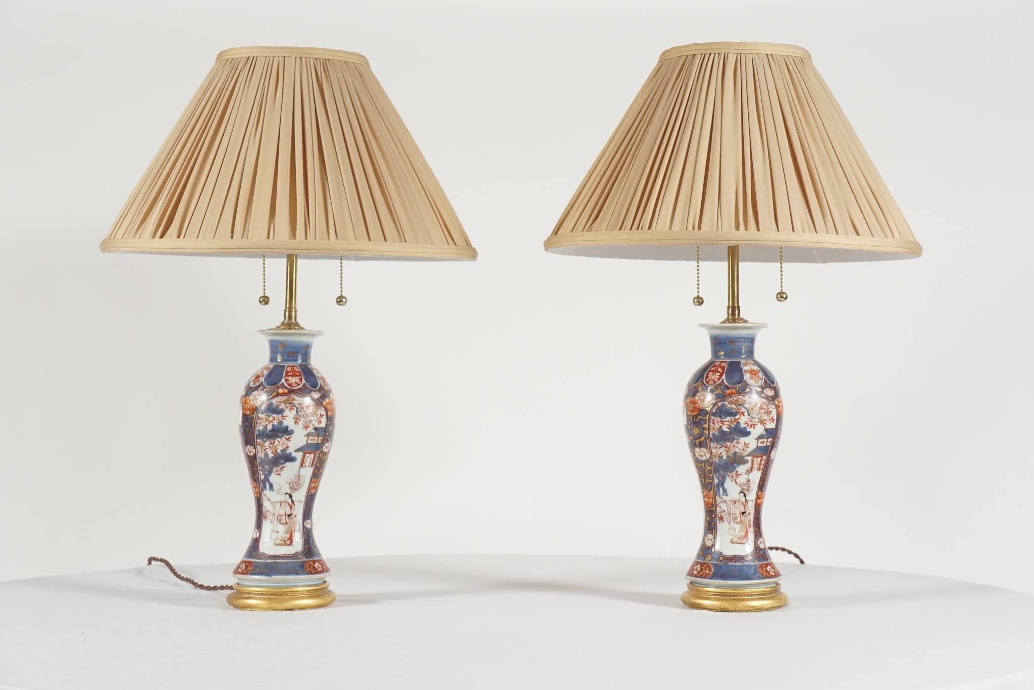 Elegant pair of early Qing Dynasty Chinese Export porcelain baluster-form garniture vases, converted to lamps circa 1930, having an Imari palette of underglaze blue, iron red, and gilding with figural, foliate, and architectural motifs in panels on