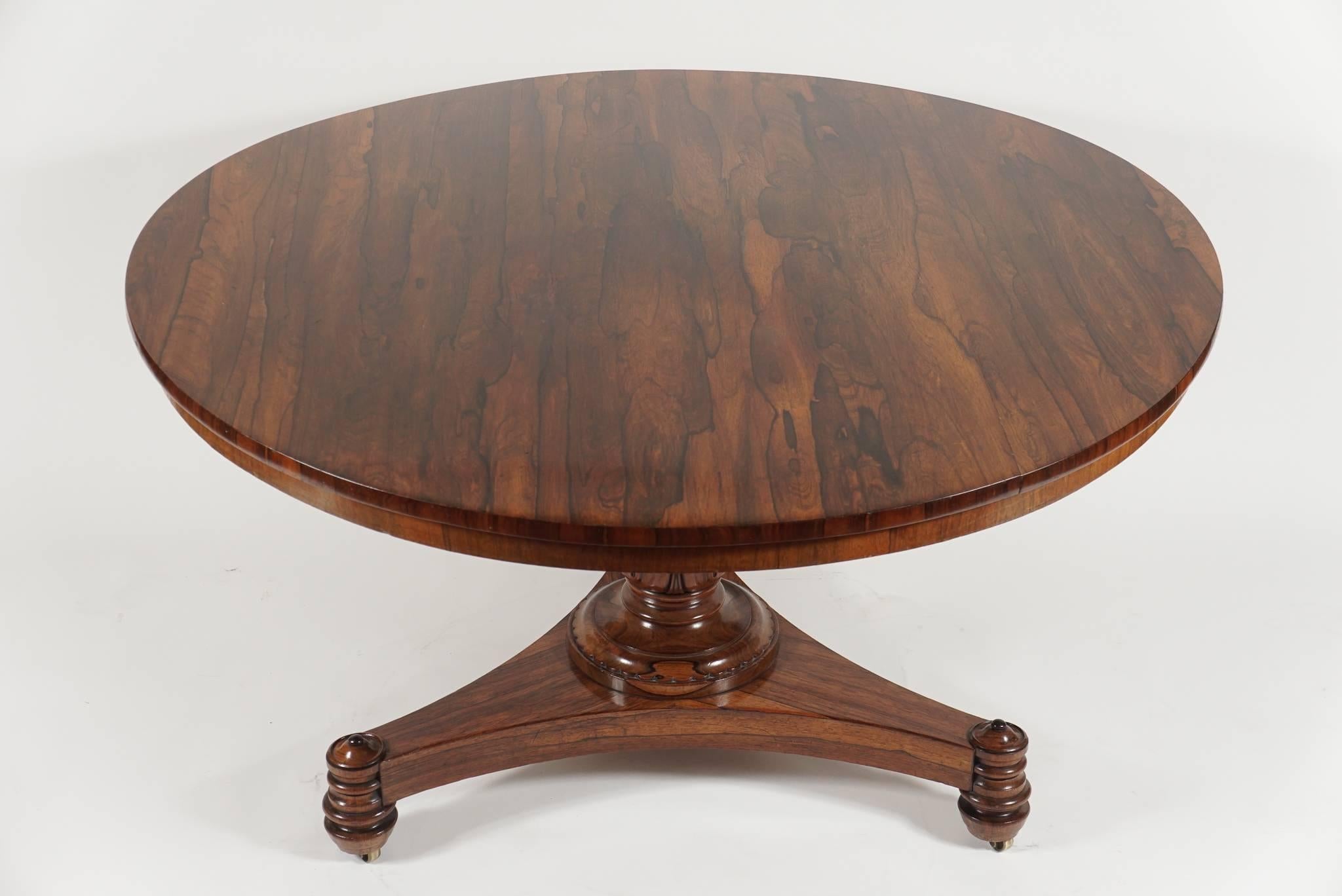 Exquisite and unusual late English Regency, William IV period, rosewood center or breakfast table of circular form having richly grained tilting top on central turned pedestal with finely carved lambs-tongue motif on circular stepped socle with
