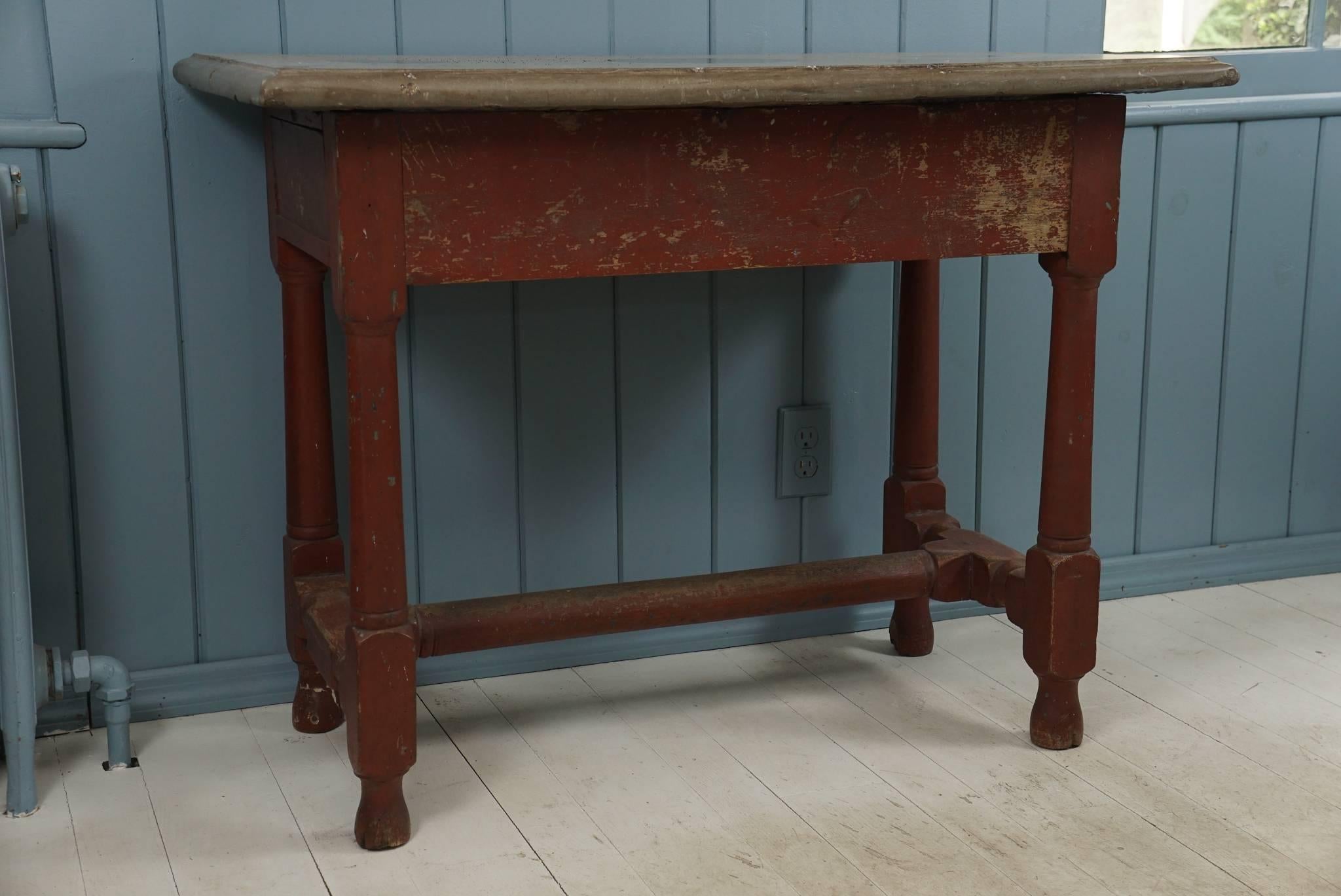 An exceptional first half 18th century Swedish Baroque table in original red paint having an O?land stone top with 'thumbnail' edge surmounting wood base with flat apron joining 'Doric' turned central supports on block and turned stretcher base.
