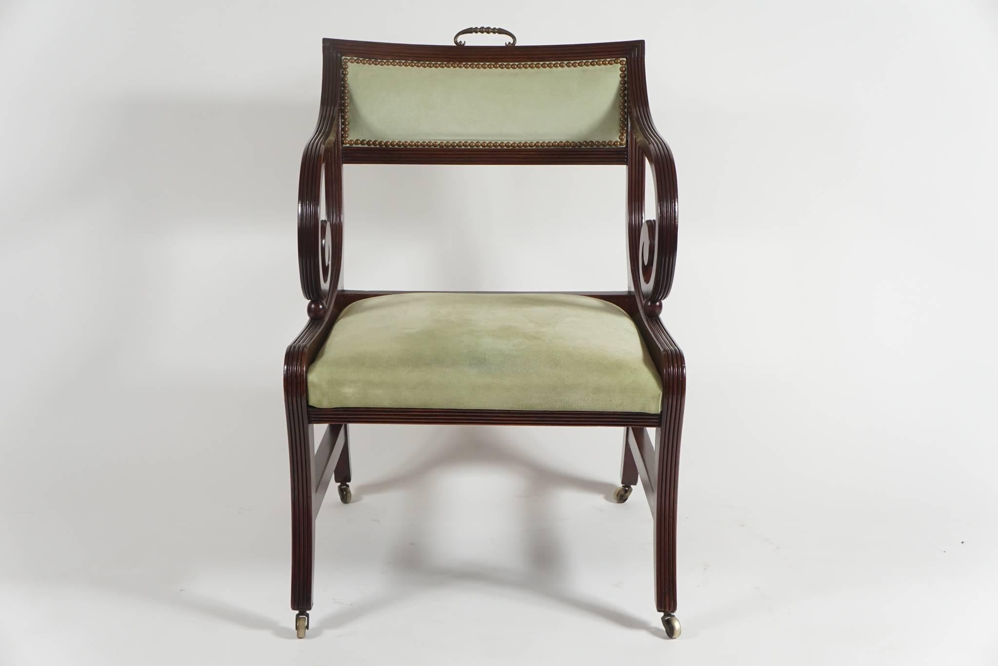 English Regency period klismos-form armchair or library chair, circa 1815, of large scale having solid mahogany frame with curved tablet form backrest with brass handle issuing reeded scrolling arms, connecting to reeded-edge frame with slip-seat,