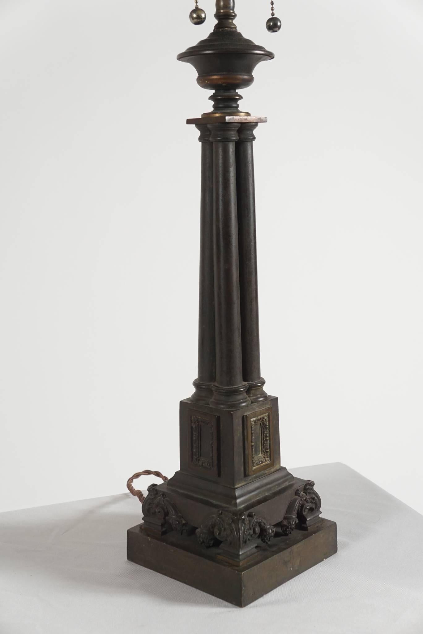 English Regency period solid bronze table lamp firmly attributed to the Birmingham firm of Thomas Messenger and Sons of clustered column-form on stepped plinth base with panel and acanthus motifs. Originally a sinumbra lamp, converted to electricity